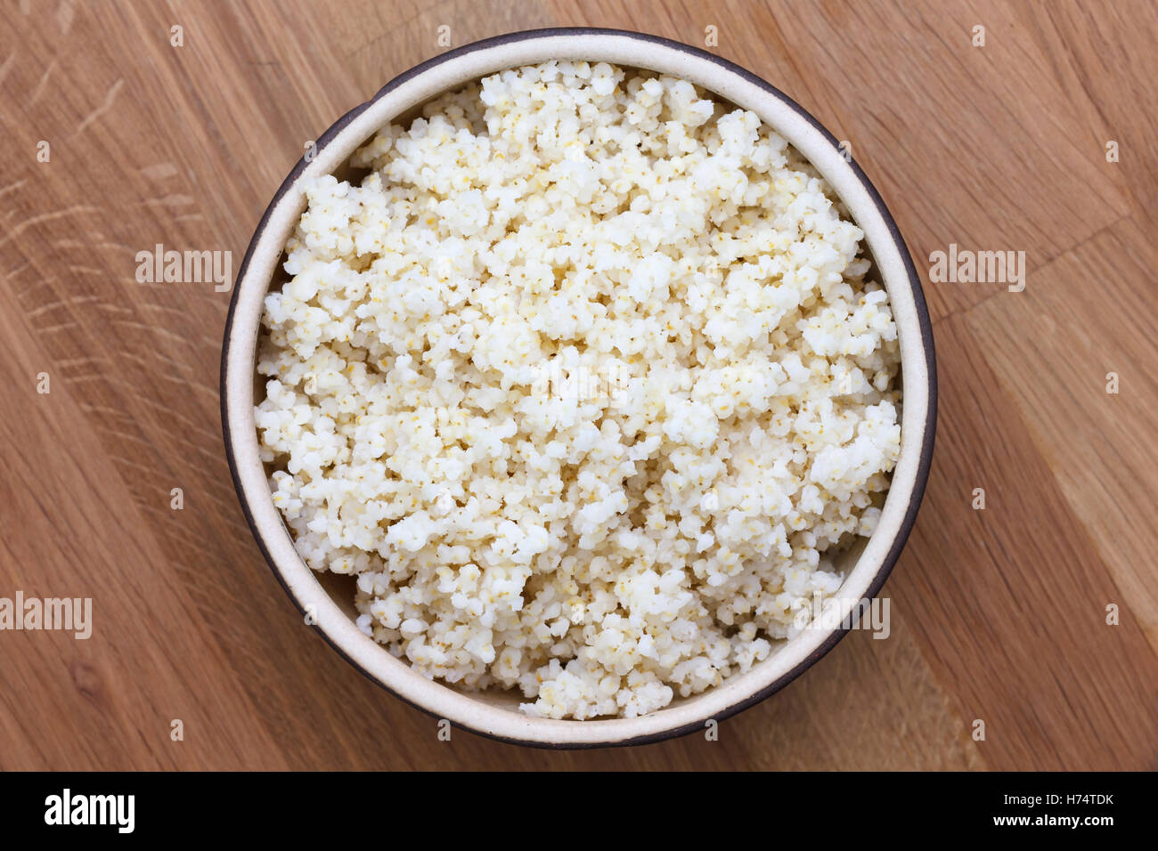 Cooked quinoa in a ceramic bowl on wood table. Stock Photo