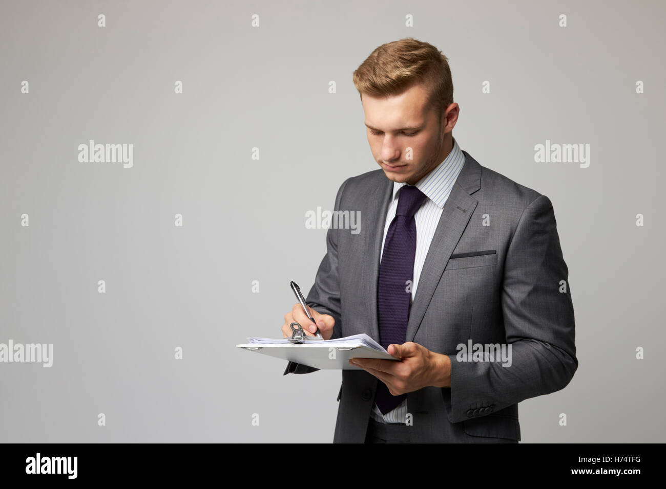 Studio Portrait Of Businessman Writing On Clipboard Stock Photo - Alamy