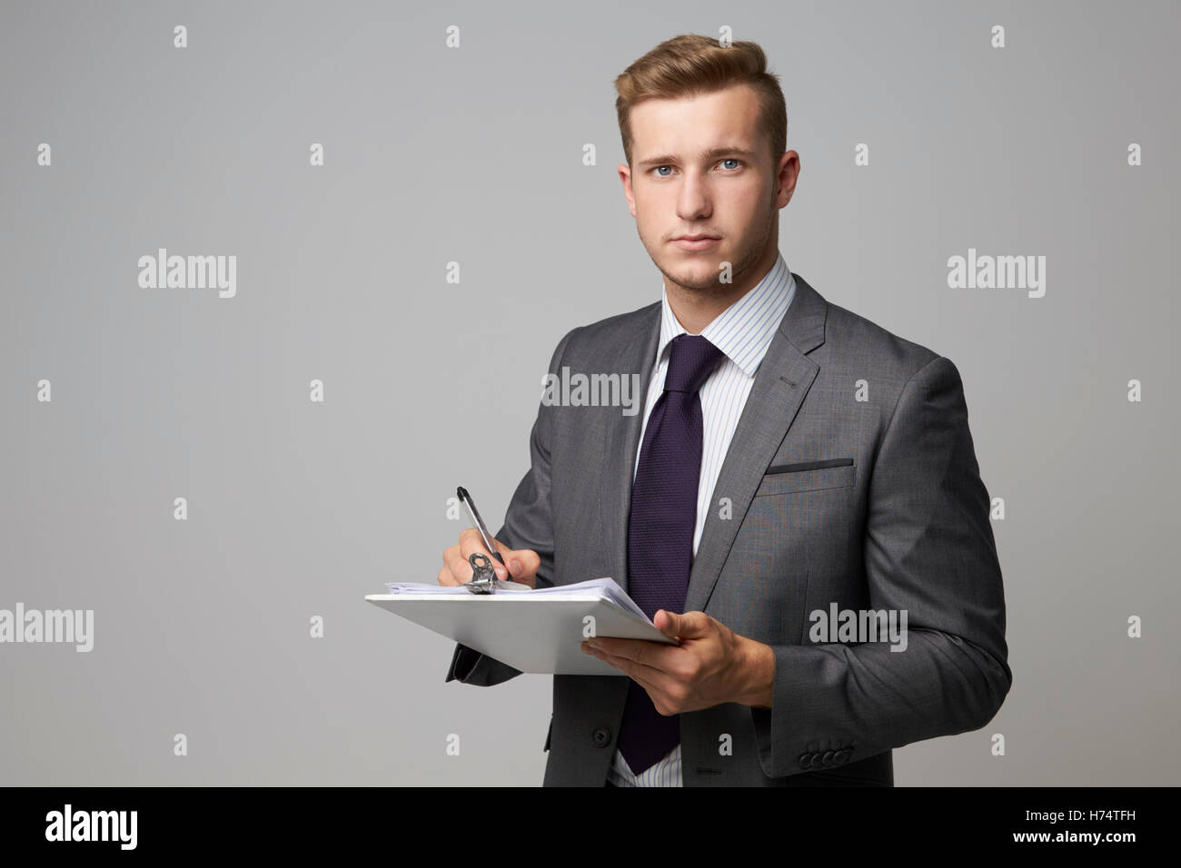 Studio Portrait Of Businessman Writing On Clipboard Stock Photo - Alamy