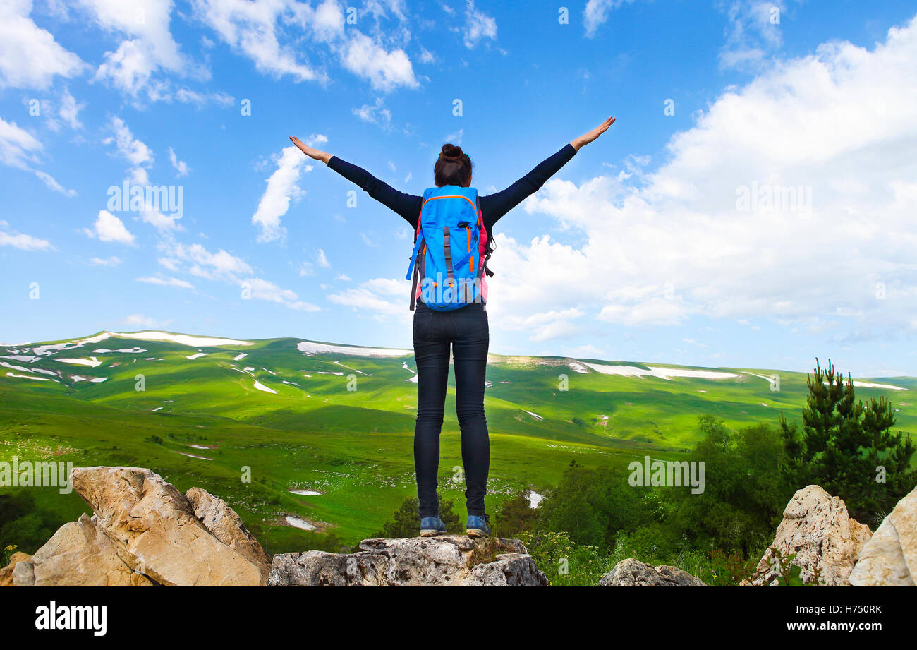 Hiker woman with backpack relaxing on top of a mountain and enjoying ...
