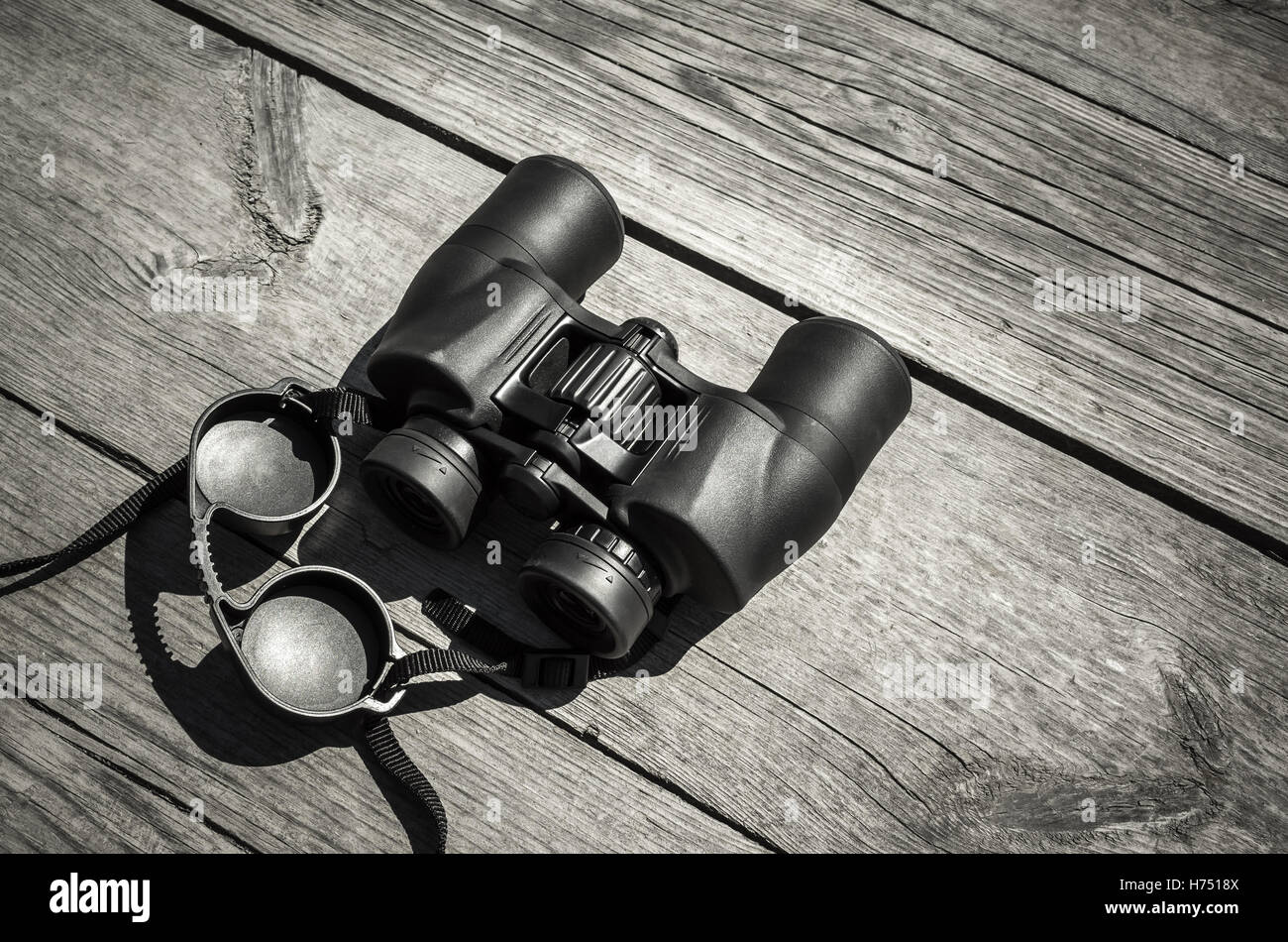 Black touristic binoculars lays on rough outdoor wooden table Stock Photo