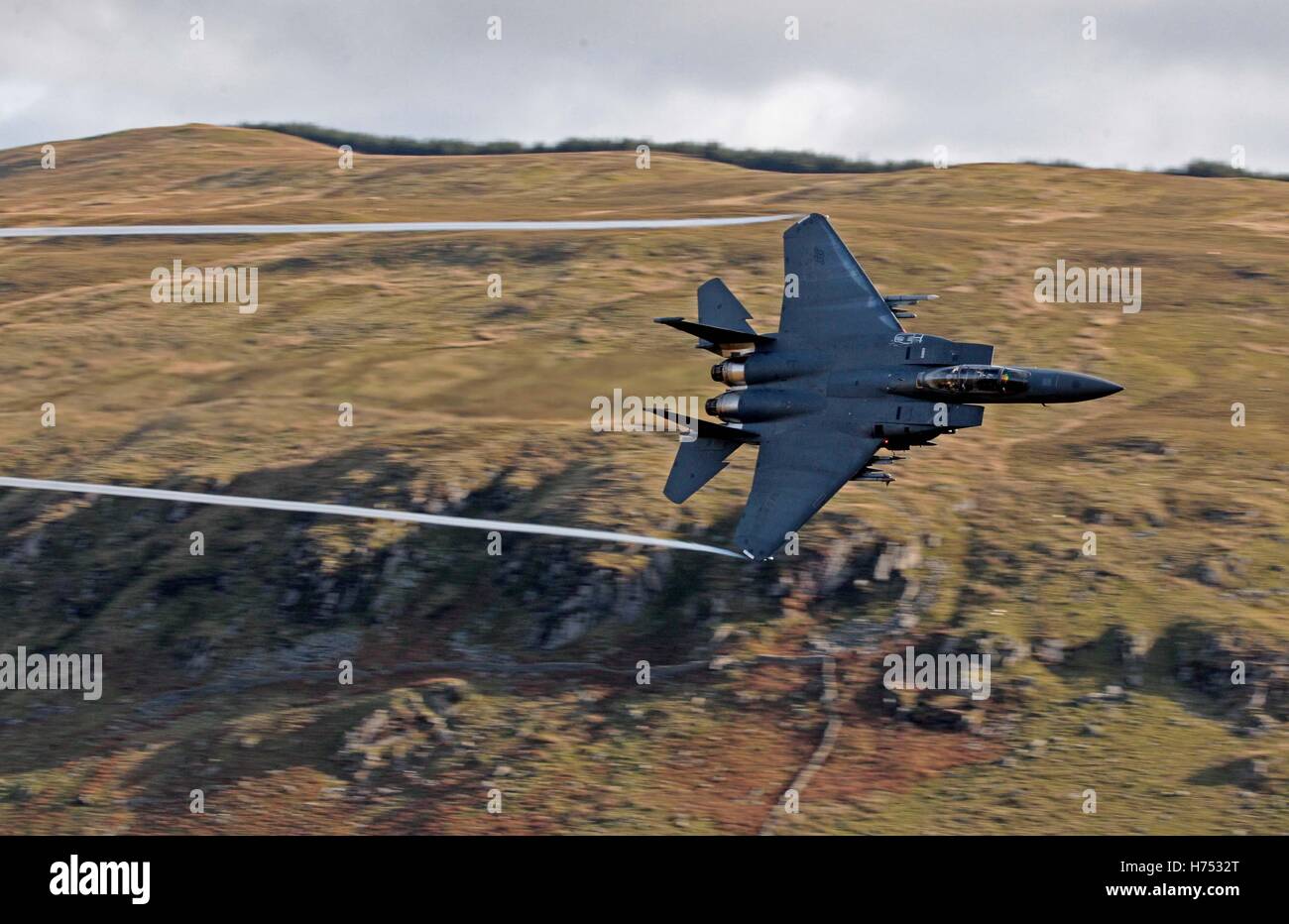 An F-15 jet is seen from Cad West, as it flies low level through the Machynlleth Loop in Wales, a series of valleys notable for their use as low-level training areas for fast jet aircraft. Stock Photo