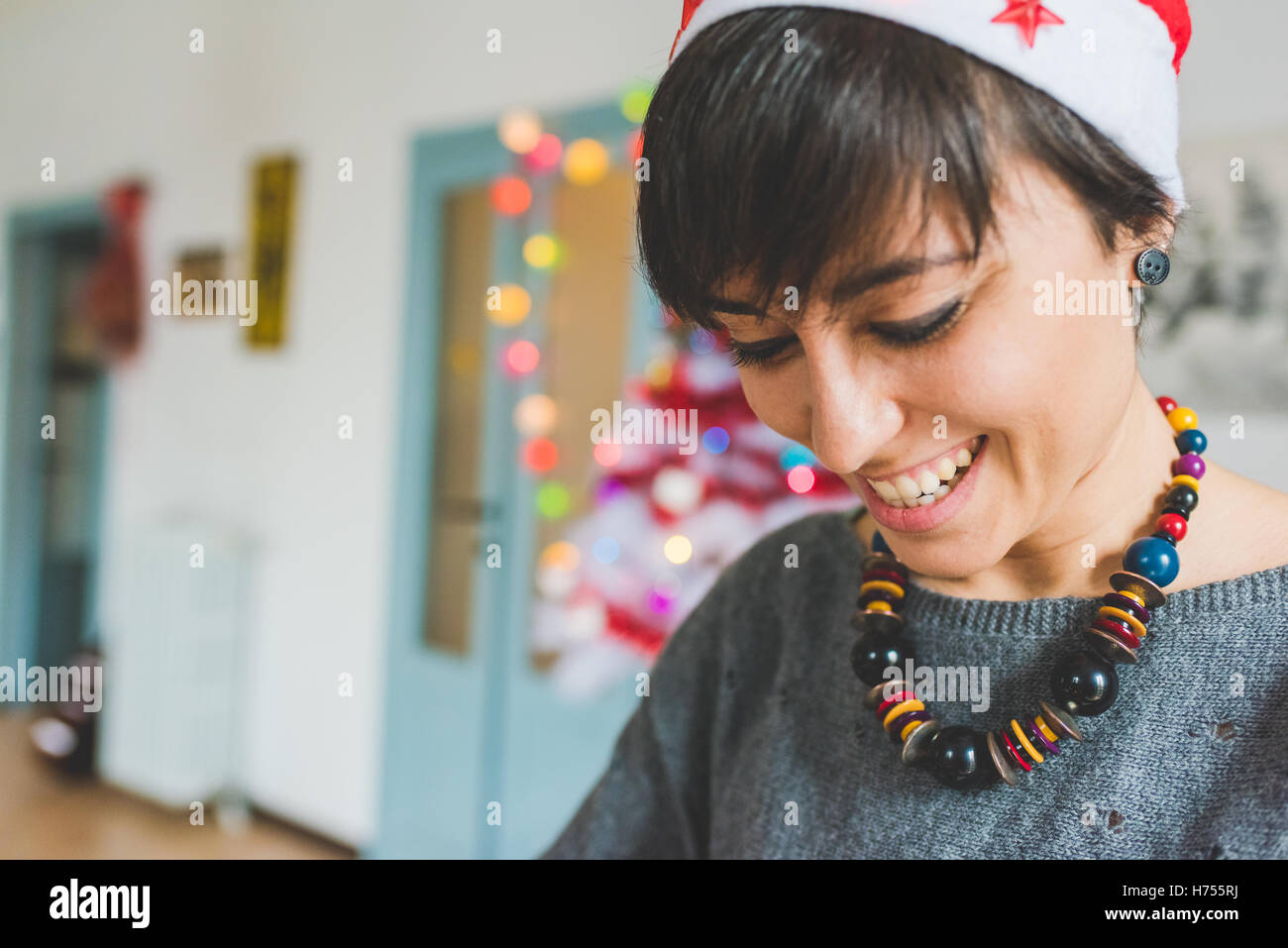 Portrait of young beautiful woman wearing christms hat having fun indoor in her apartment - christmas, happiness, celebration co Stock Photo