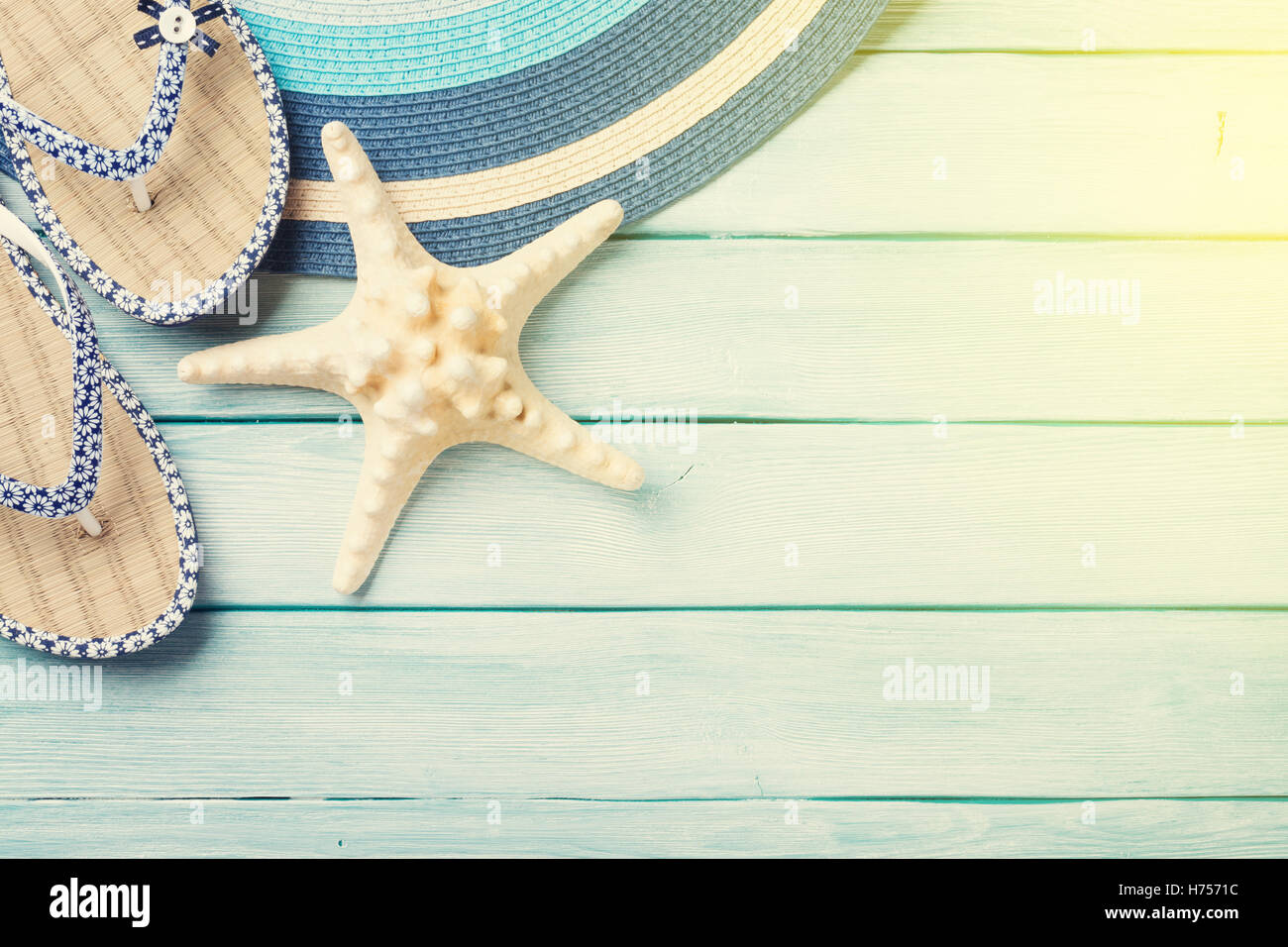 Beach accessories. Flip flops, hat and starfish on wooden background ...