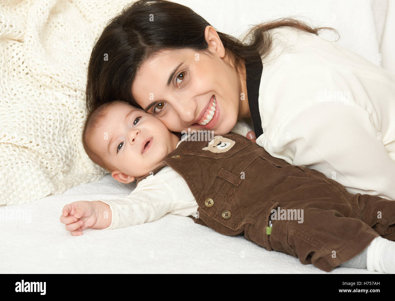 Mother lie with baby on bed, happy family portrait on white background
