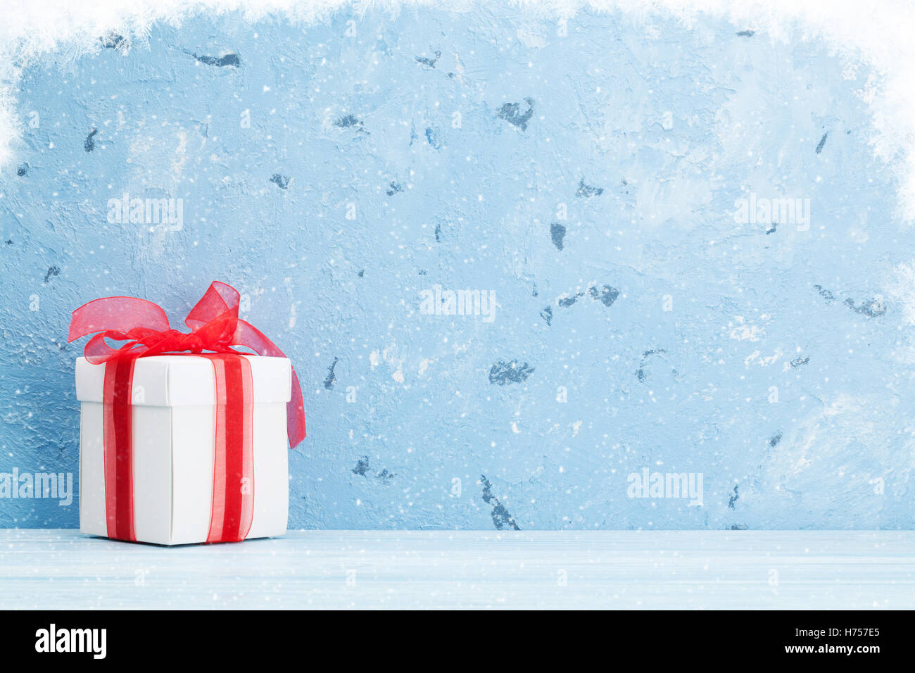 Christmas gift box and snow in front of stone wall with copy space Stock Photo