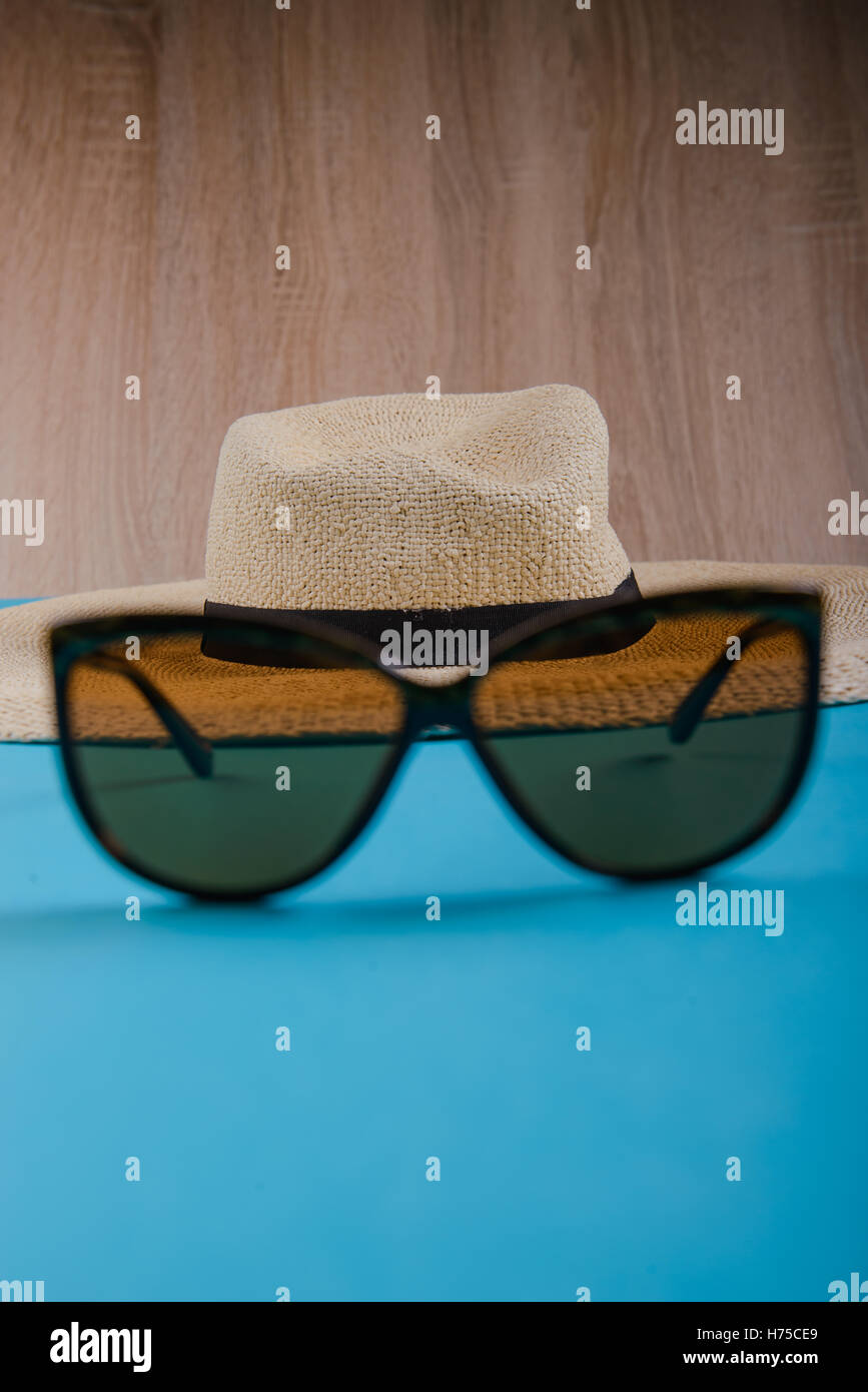 Straw hat and sunglasses on blue background. beach equipment Stock ...