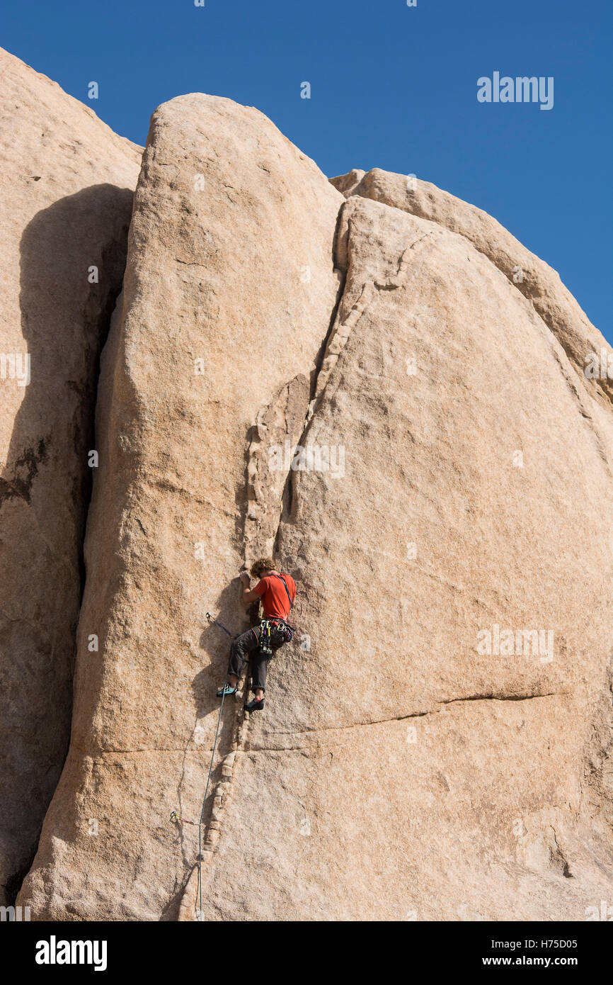 A 20 something man climbing a boulder, Joshua Tree National Park Stock Photo