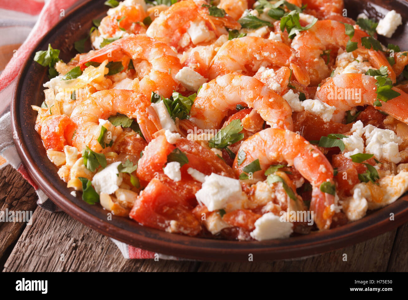 Greek cuisine: shrimp Saganaki with feta cheese and tomatoes close-up