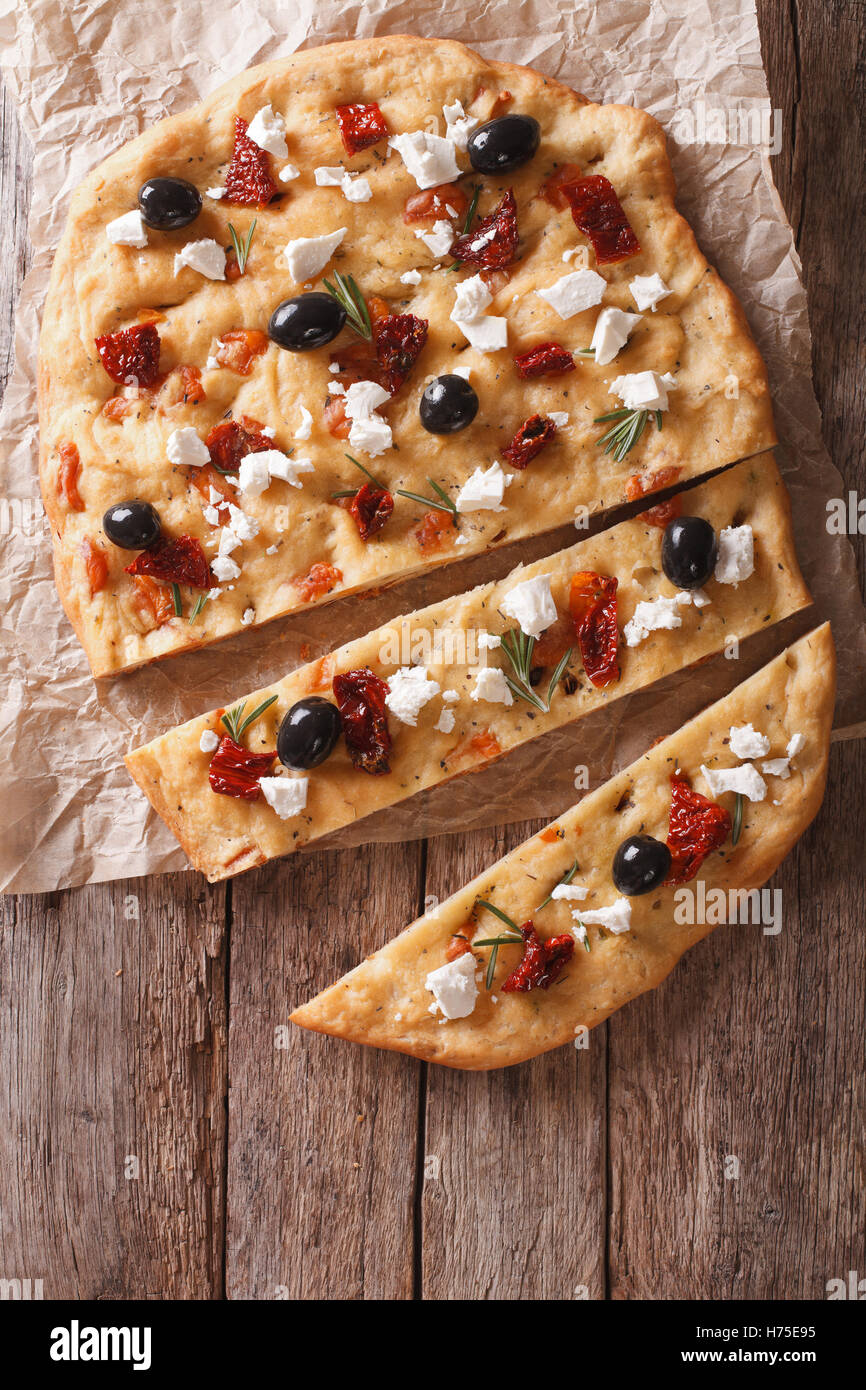 Focaccia with dried tomatoes, feta and olives on the table. vertical view from above Stock Photo