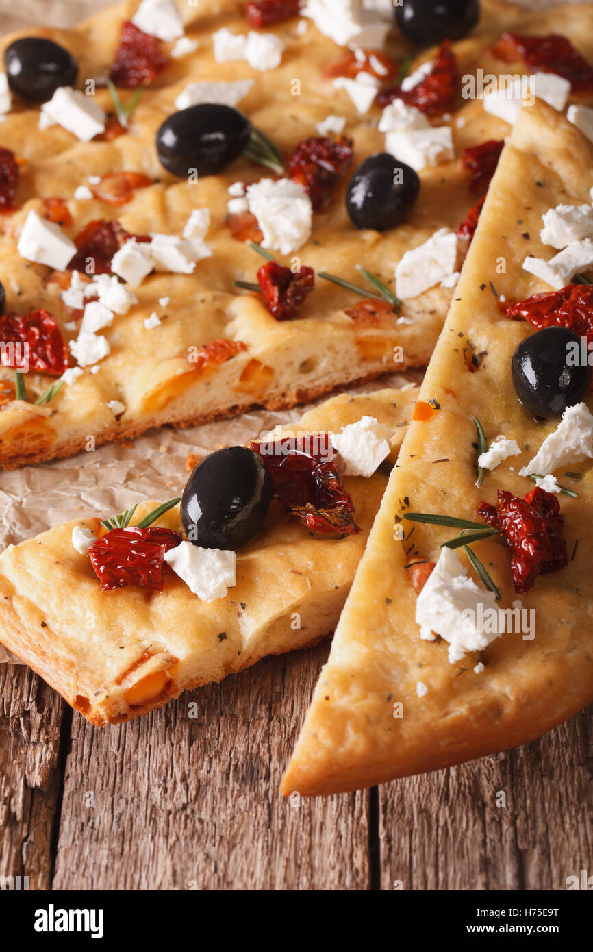 Focaccia with dried tomatoes, feta and olives on the table. macro vertical Stock Photo