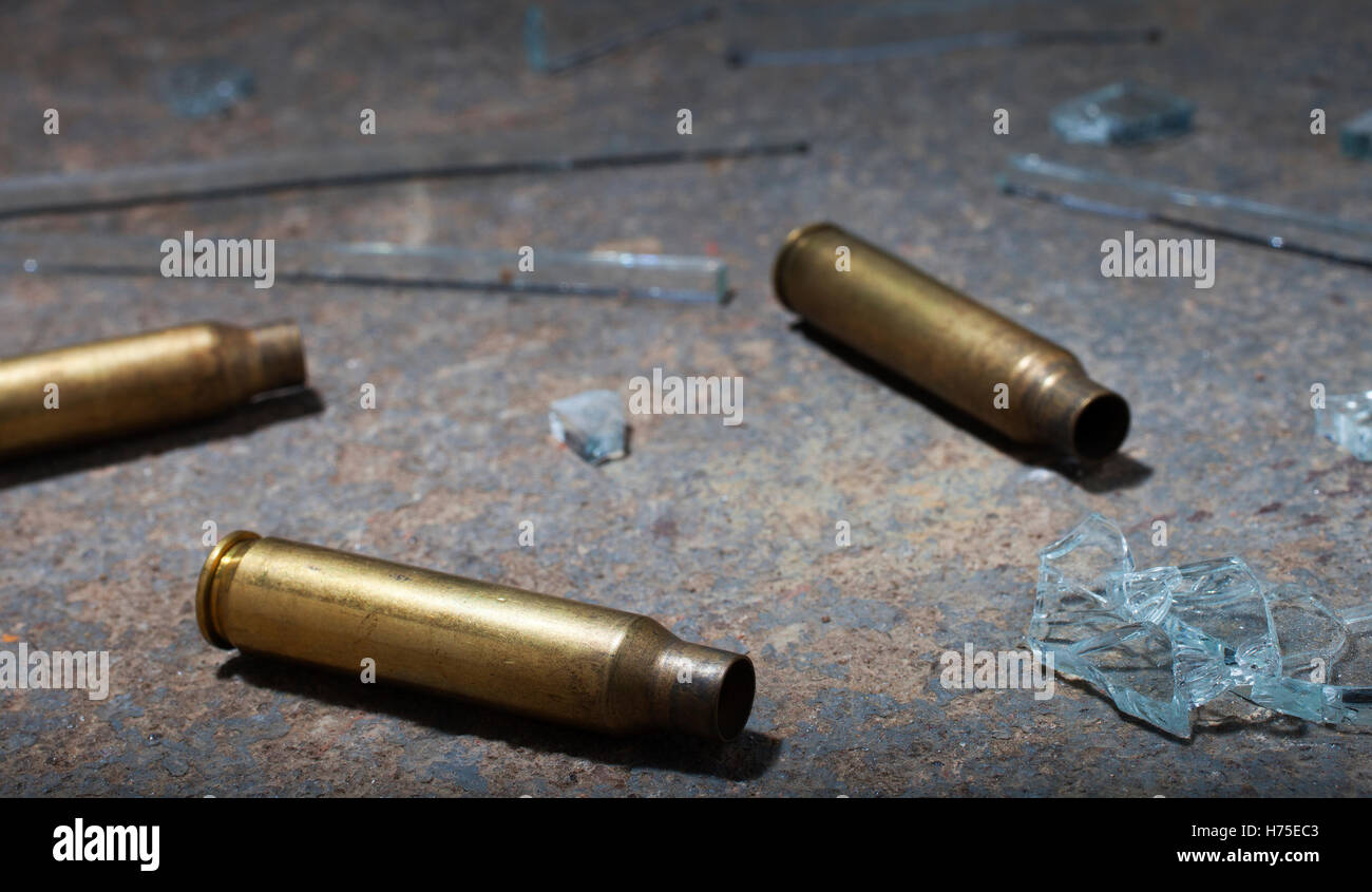 Three rifle cartridges on concrete with broken glass Stock Photo