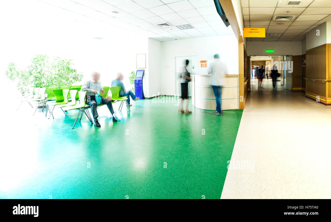 View of the registration desk, waiting area and a corridor in modern hospital with blurred figures of patients with a copy space Stock Photo
