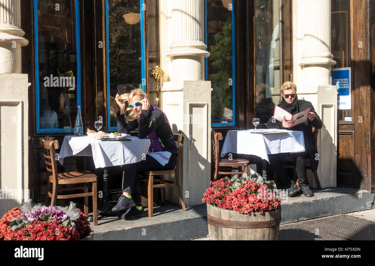 Two blond diners eating an alfresco lunch alone at a Soho restaurant in New York City Stock Photo
