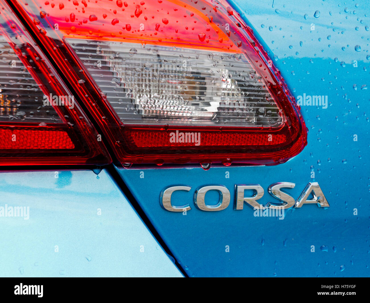 Close up view of metallic blue 2016 model Vauxhall Corsa car with water drops on body and rear light cluster Stock Photo