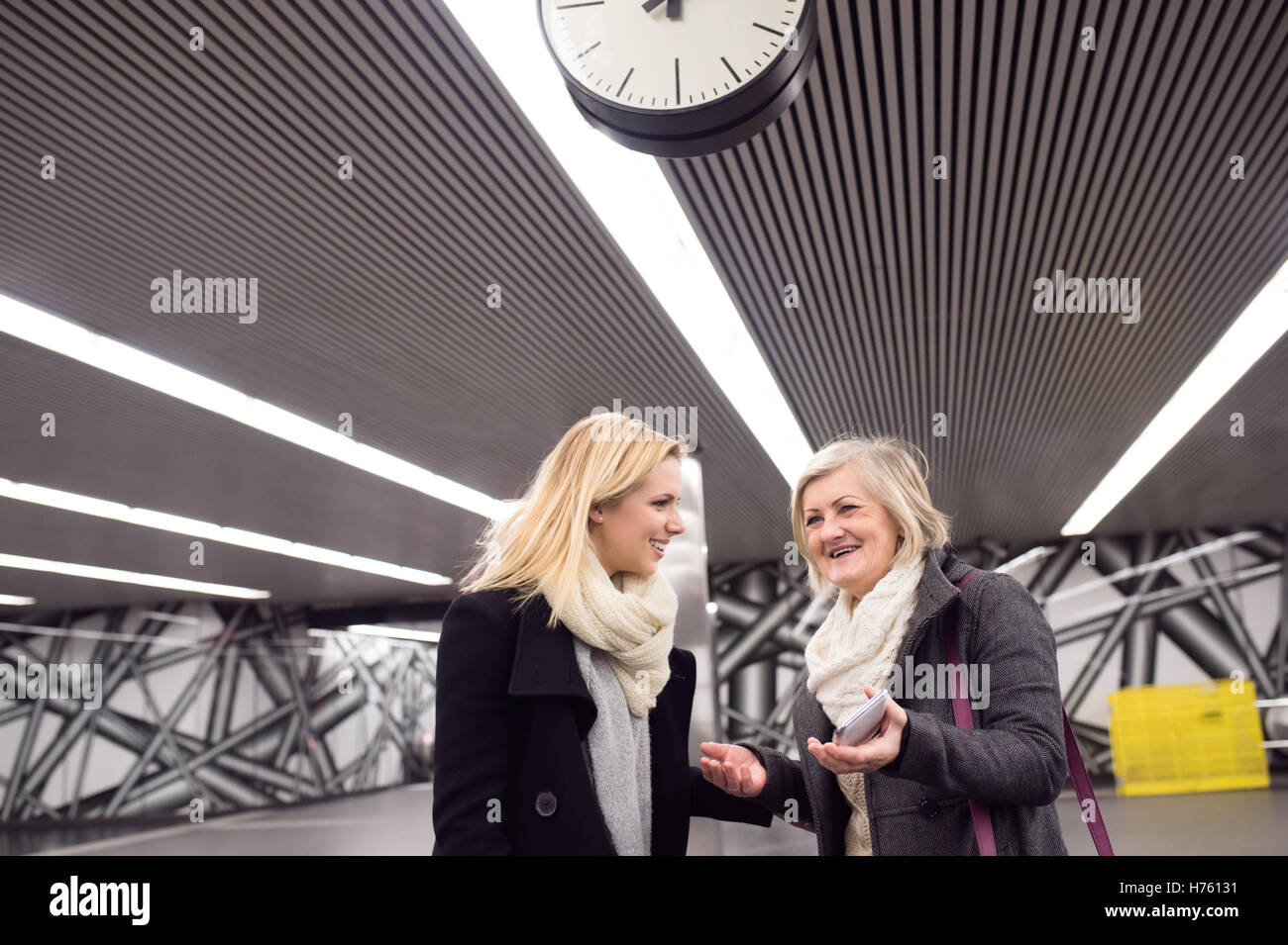 Two beautiful women standing at the underground platform, talkin Stock Photo