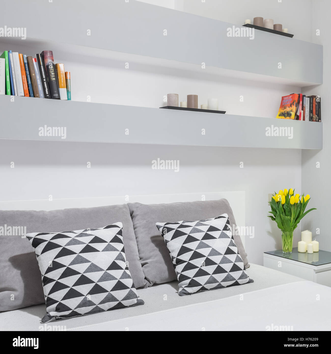 White Bedroom With Wall Bookshelf And Double Bed Stock Photo