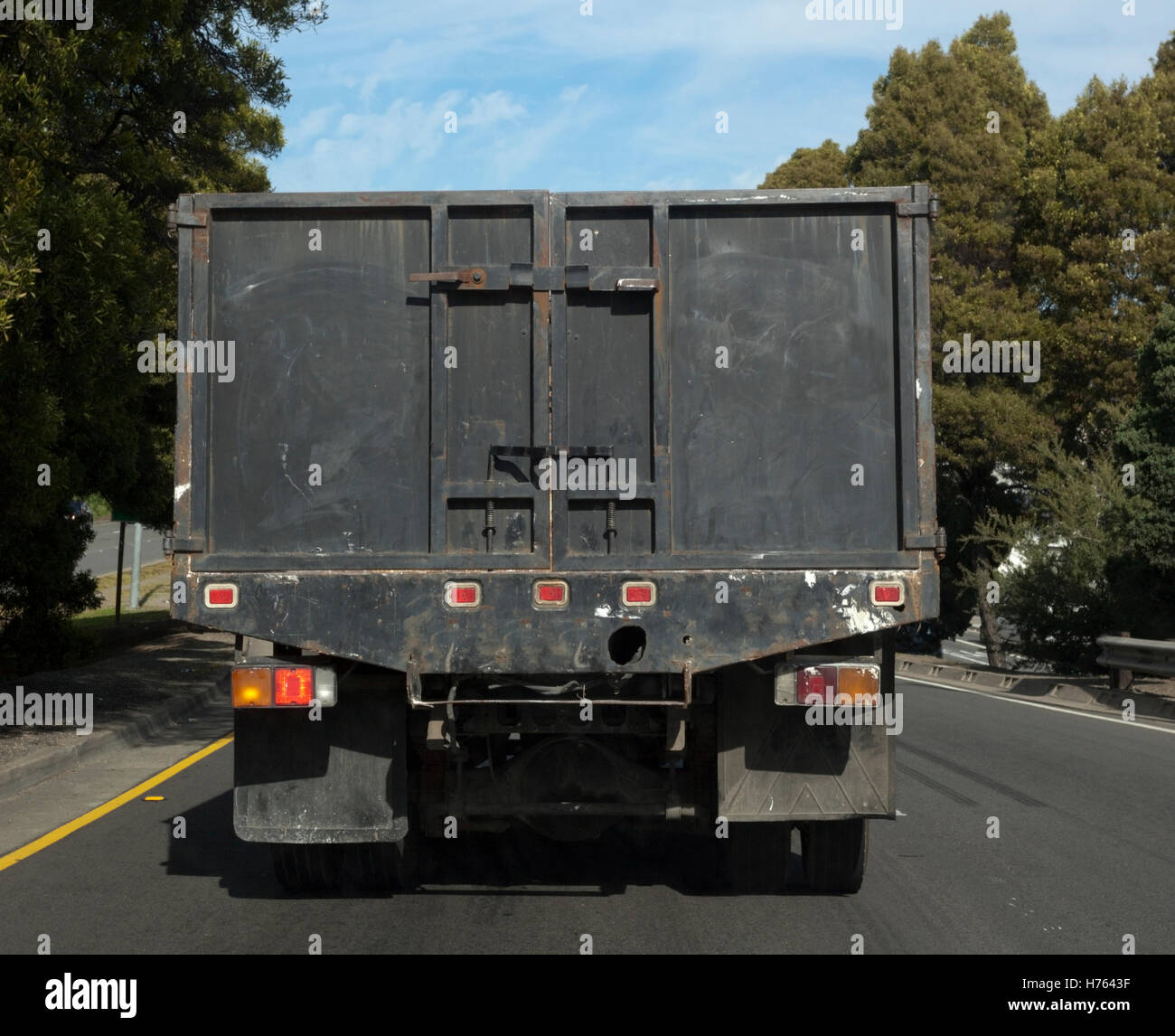 Rear view of black construction truck on rural road Stock Photo