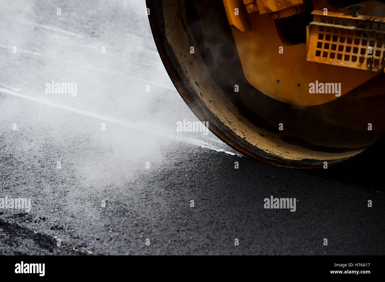 Asphalt paving with a steel wheel roller. Steam coming out from asphalt. Stock Photo