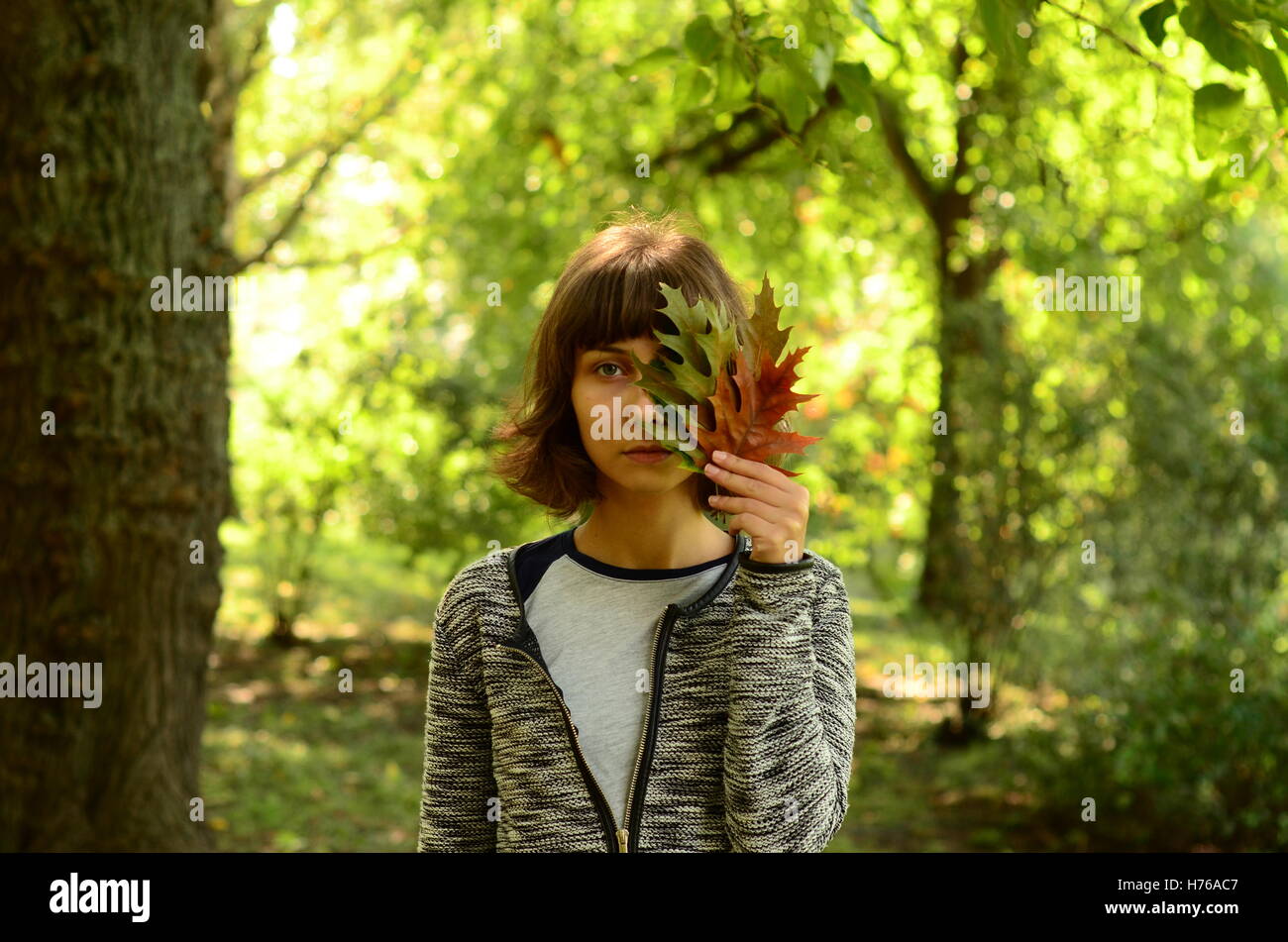 Portrait of woman holding autumn leaves in front of her face Stock ...