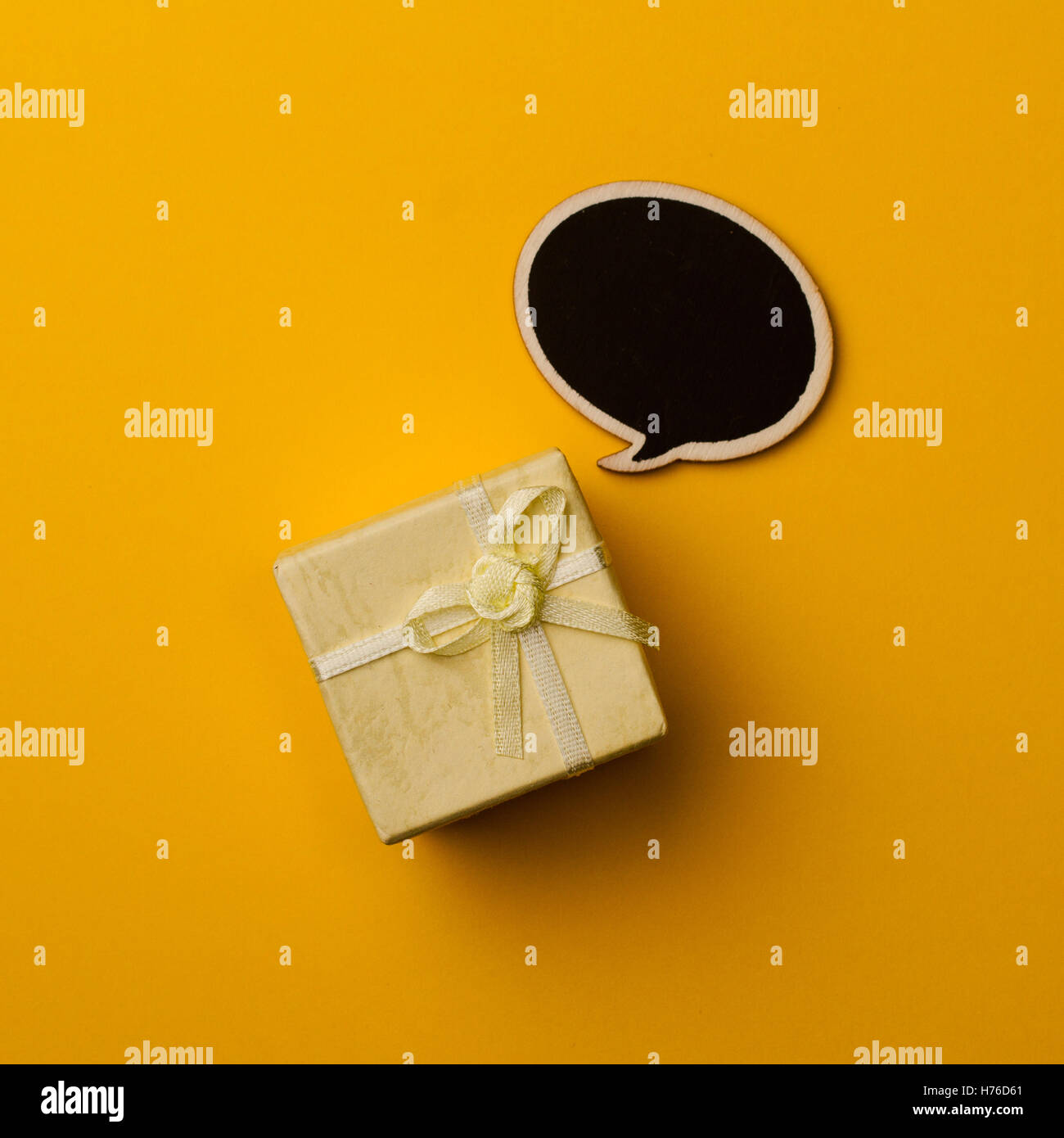 top view of small gift box on blue background with wooden black chalk board speech bubble for text Stock Photo
