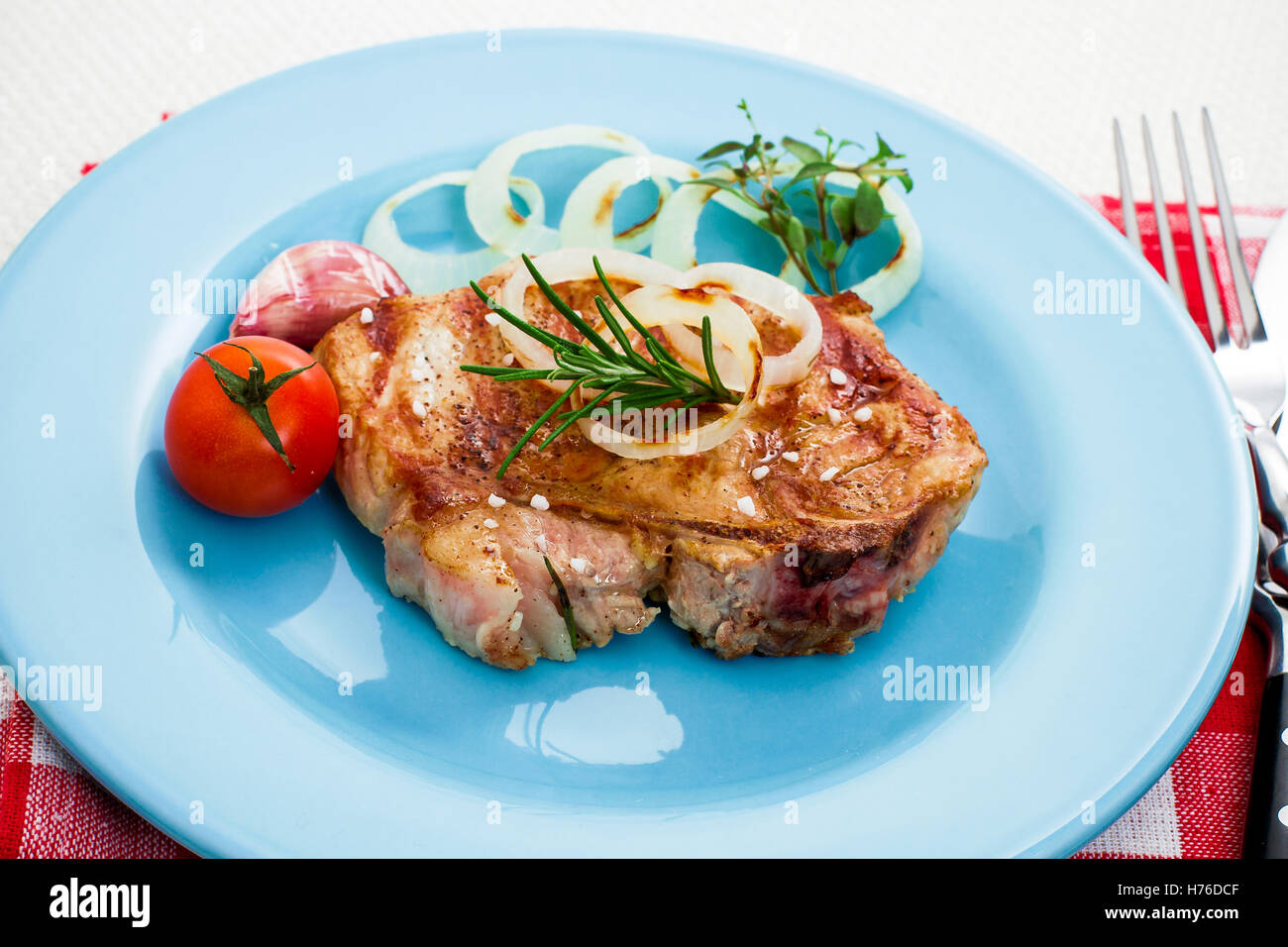 Juicy grilled pork chop with onion rings, stylish tinted Stock Photo