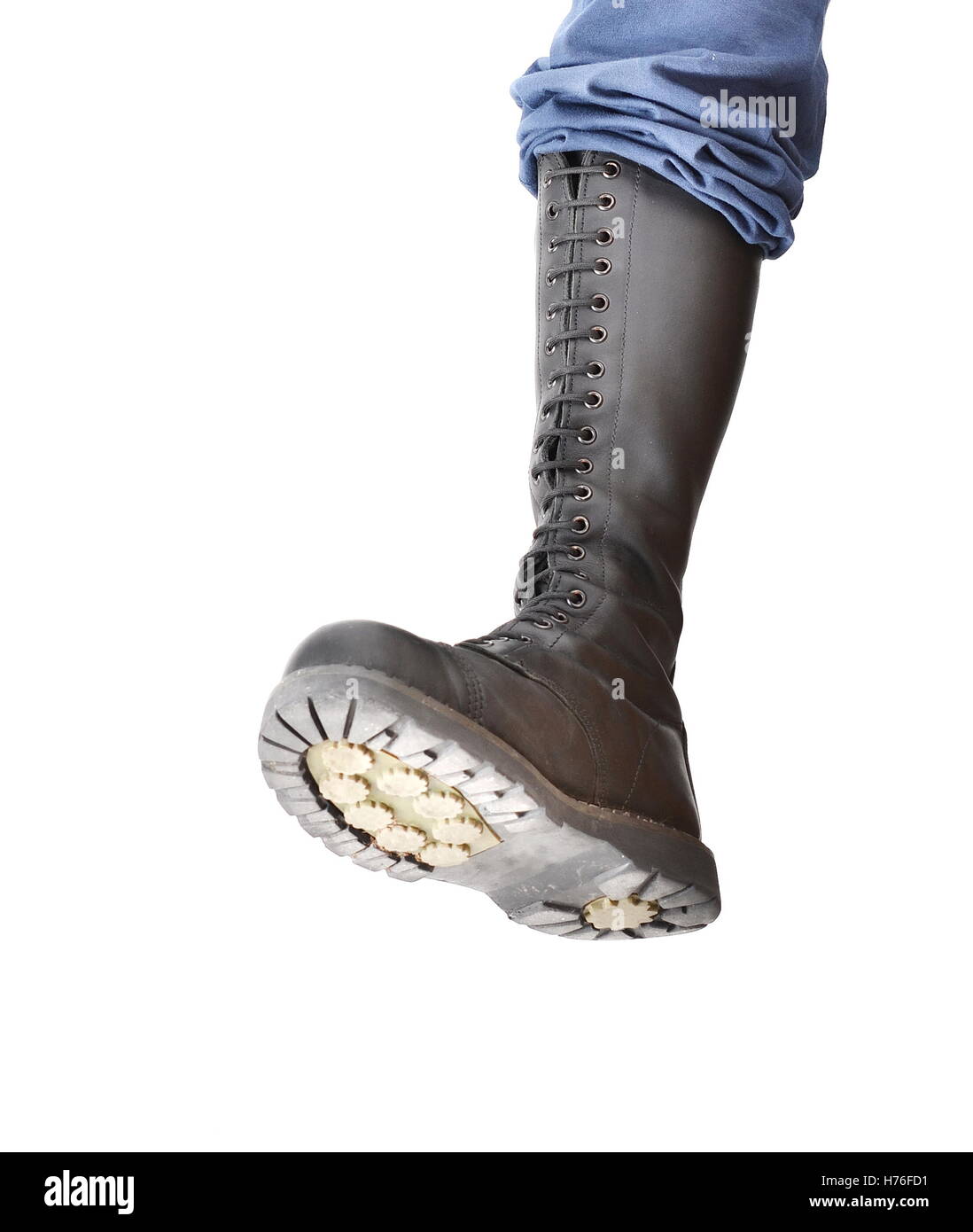 A tall lace-up combat boot stomping with the sole visible Stock Photo