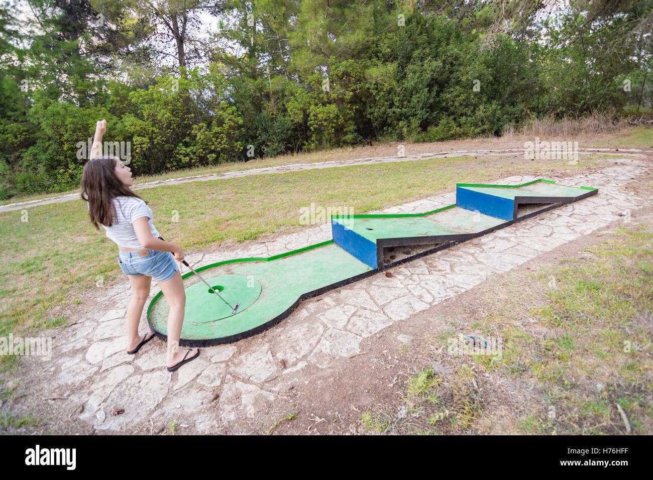 Teenage girl playing outdoor miniature golf in a Galilee forest in the north of Israel Stock Photo