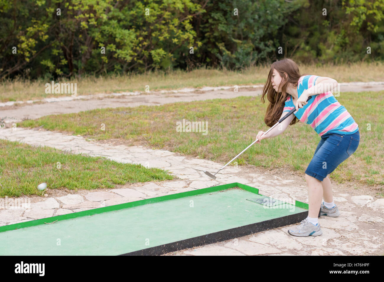 Young woman playing outdoor miniature golf in a Galilee forest in the north of Israel Stock Photo