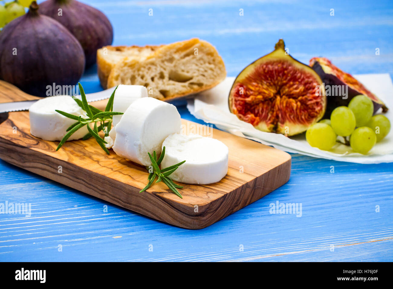 Feta cheese with ripe figs and grapes on blue, top view Stock Photo