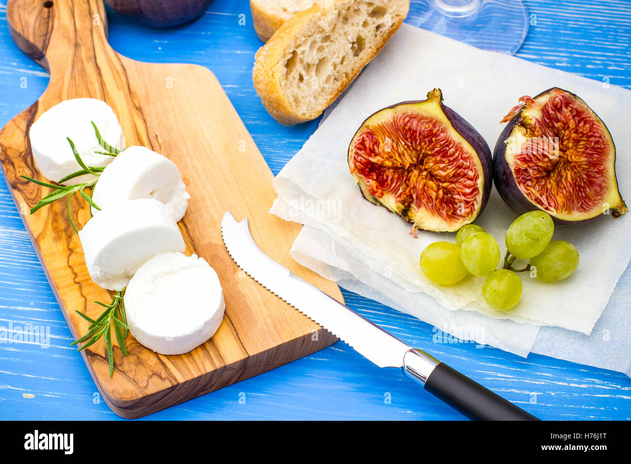 Goat cheese with ripe figs and wine on blue, top view Stock Photo