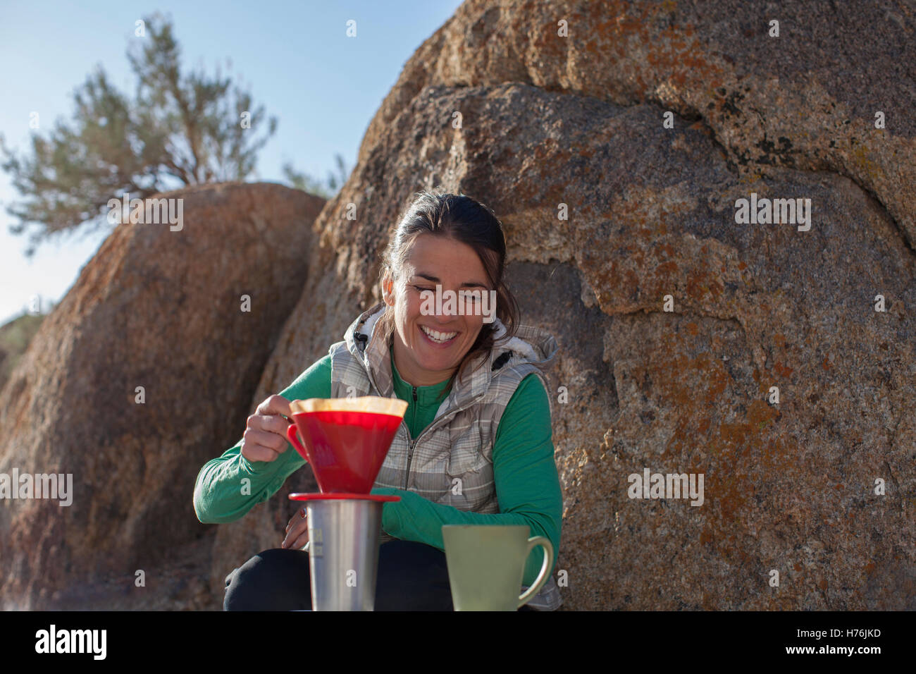 An adult woman making coffee outdoors while camping Stock Photo