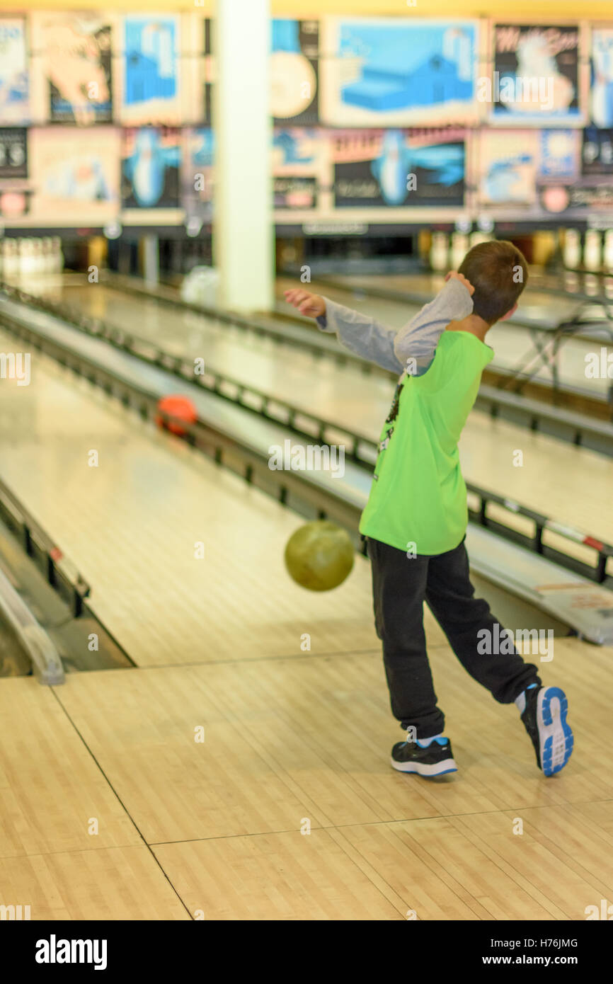 An 8 year old boy enjoying a game of bowling in a retro style bowling alley near Tel Aviv, Israel featuring old-time bowling add Stock Photo