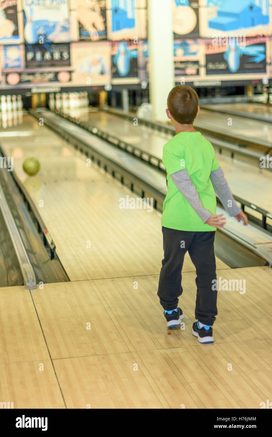 An 8 year old boy enjoying a game of bowling in a retro style bowling alley near Tel Aviv, Israel featuring old-time bowling add Stock Photo