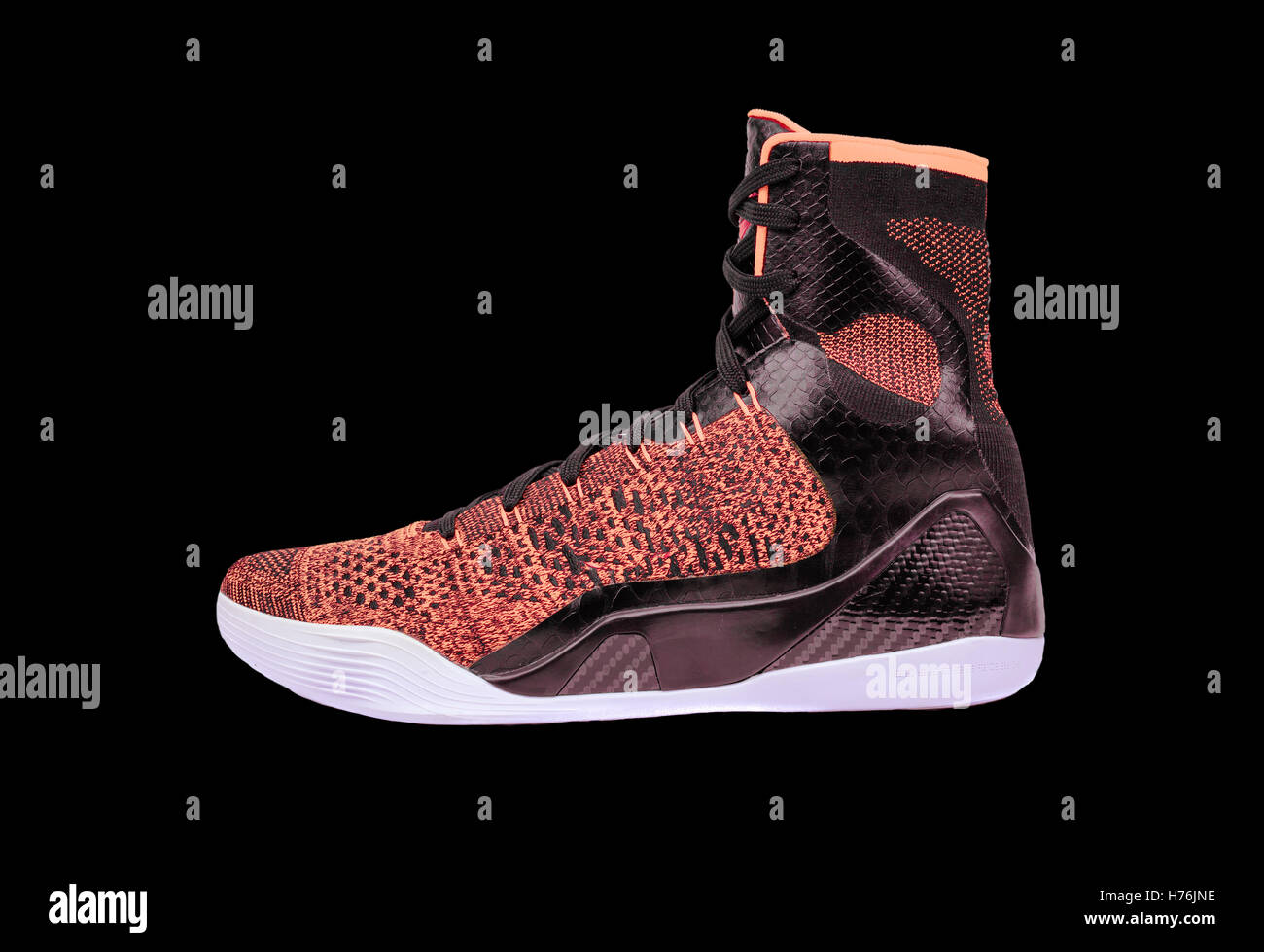 Ultra modern high-top orange and black basketball shoe sneaker, isolated on black Stock Photo
