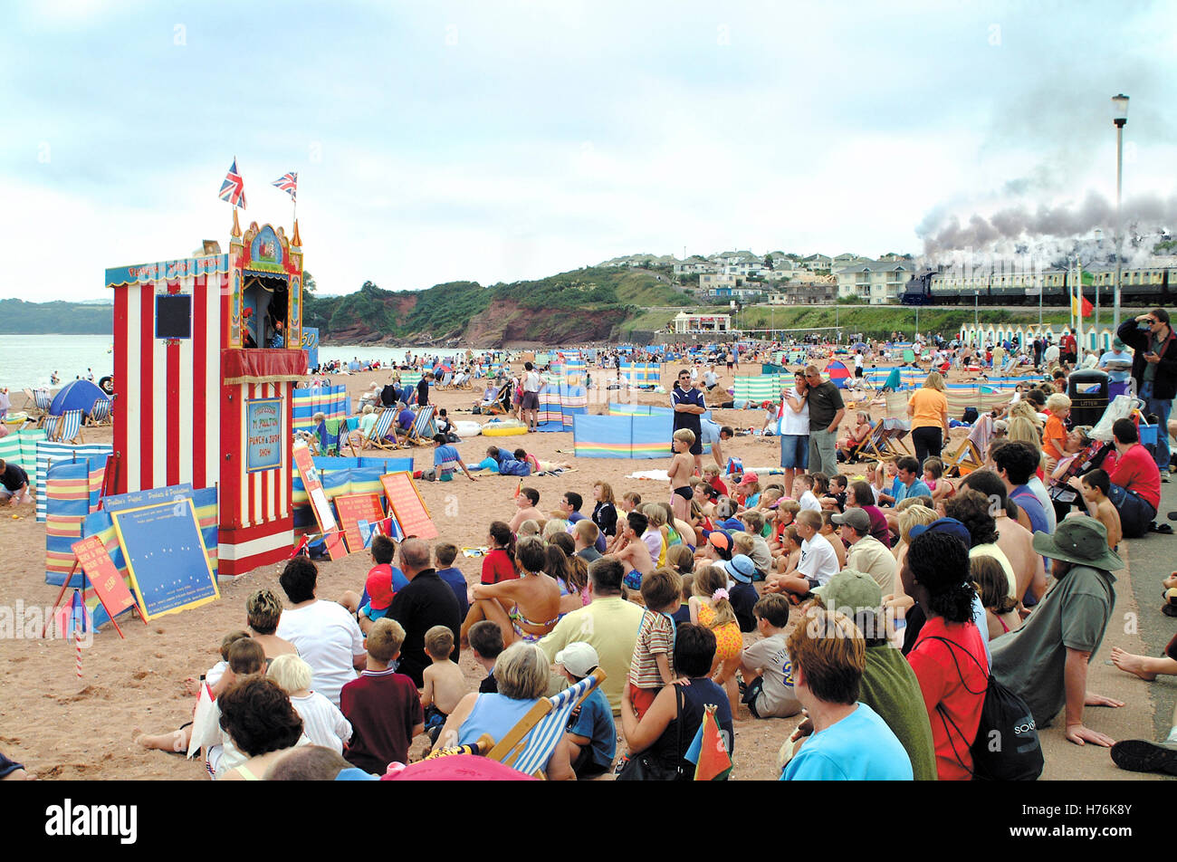 Children watching Punch & Judy with Steam train in the background at Goodrington Sands near