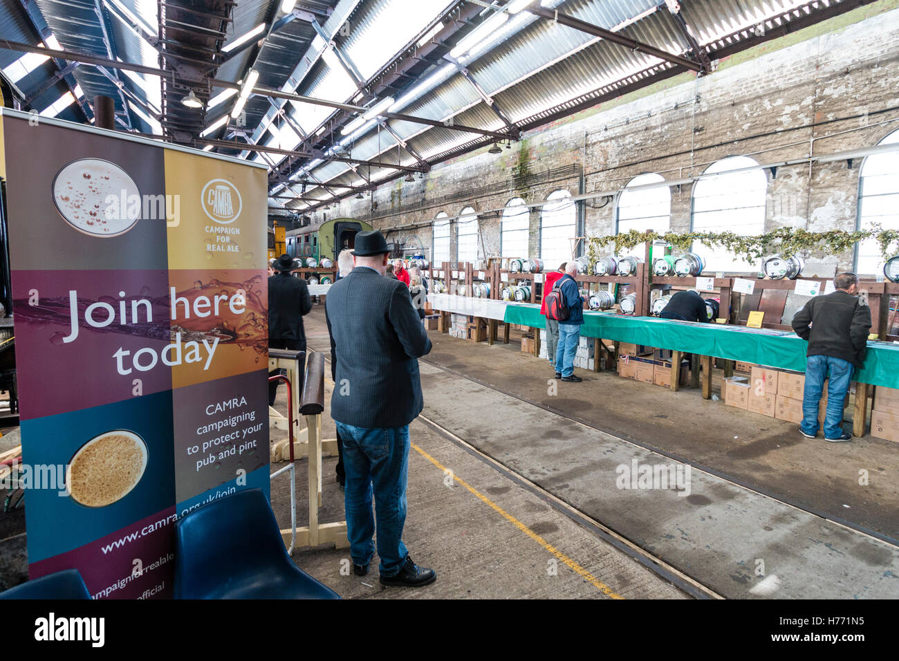 England, Tunbridge Wells. CAMRA real ale beer festival in old locomotive shed. Sign, 'join here today' at entrance, and then hall with few people. Stock Photo
