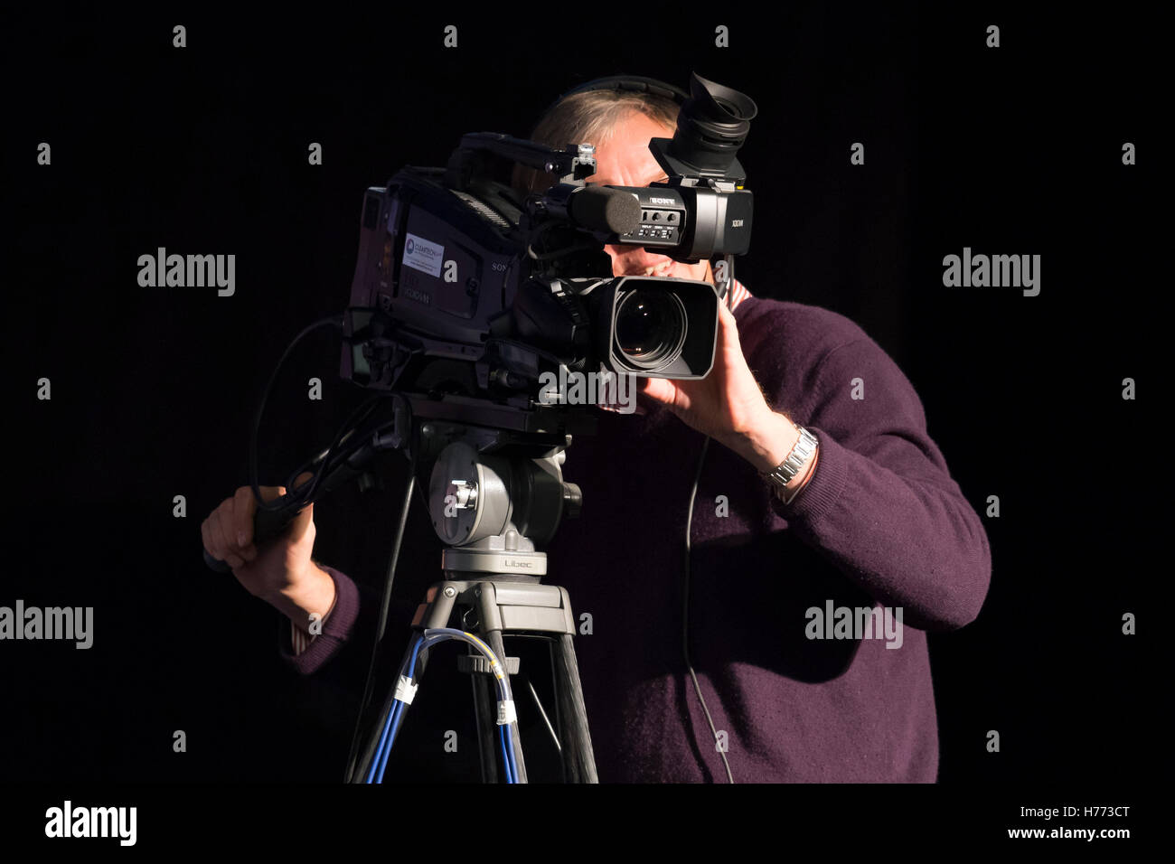A TV cameraman operating a broadcast camera. Stock Photo