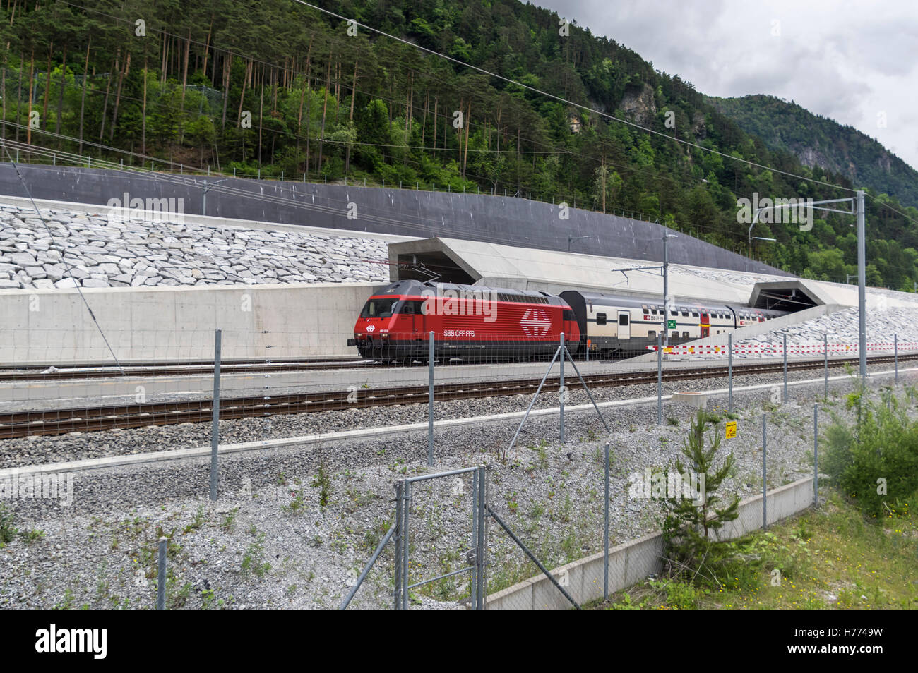 SBB passenger train with a red Re 460 locomotive leaves the 57 km long Gotthard base tunnel at the north portal in Erstfeld, Switzerland. Stock Photo