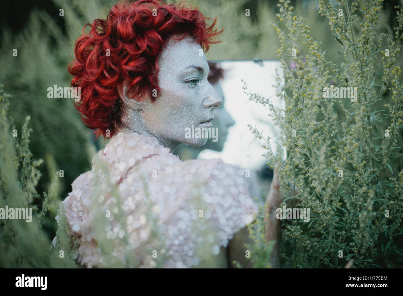Portrait of a woman with a painted silver face and red hair Stock Photo