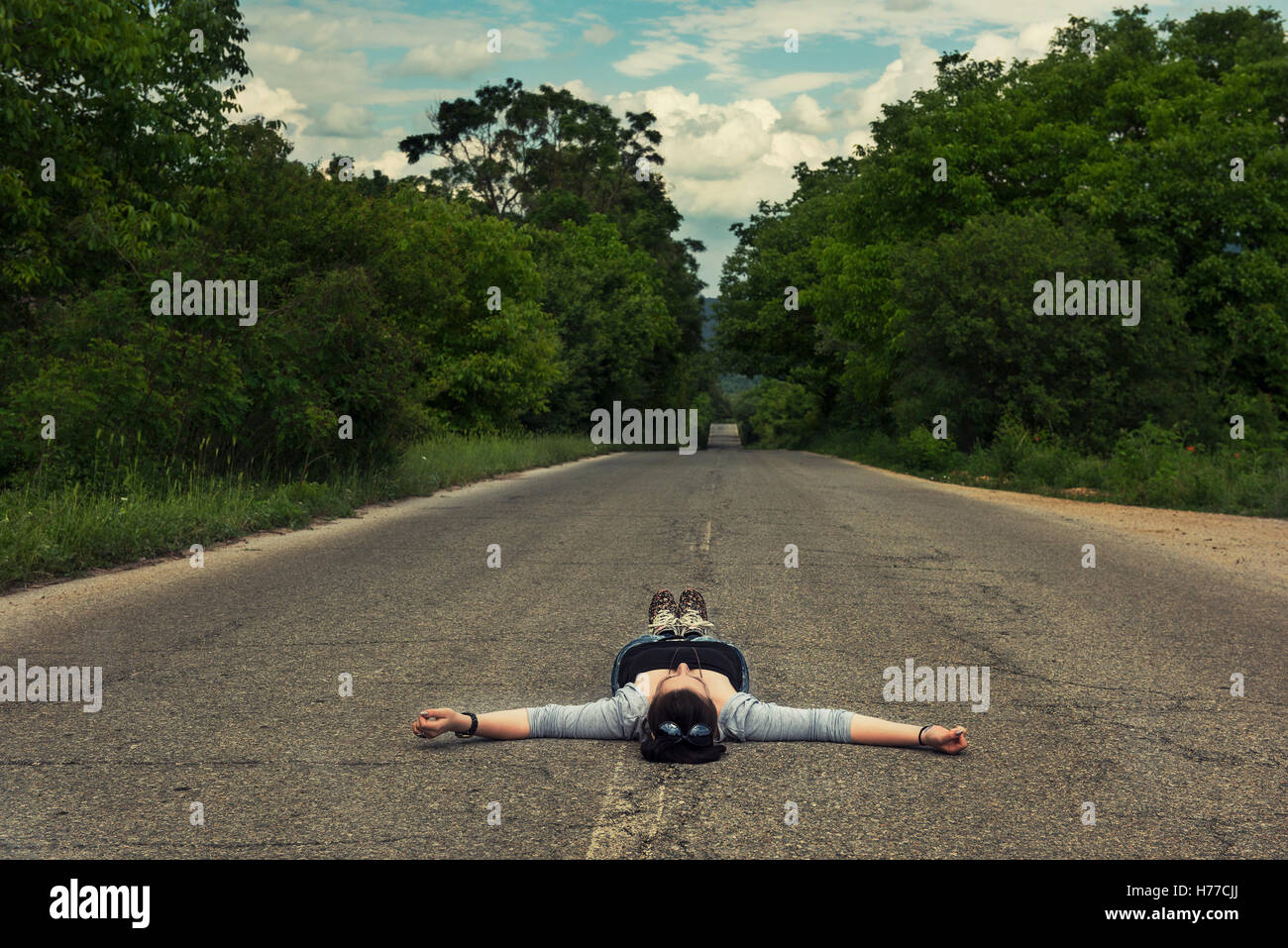 Woman lying in the middle of the road Stock Photo