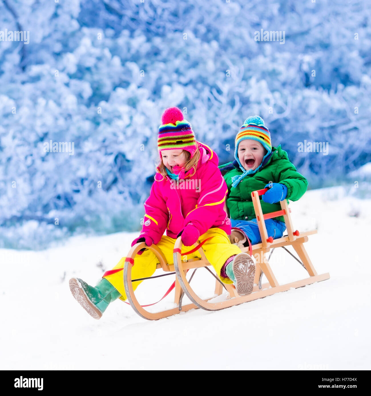 Infant Sleigh Riding Little girl and boy enjoy a sleigh ride. Child sledding. Toddler kid ...