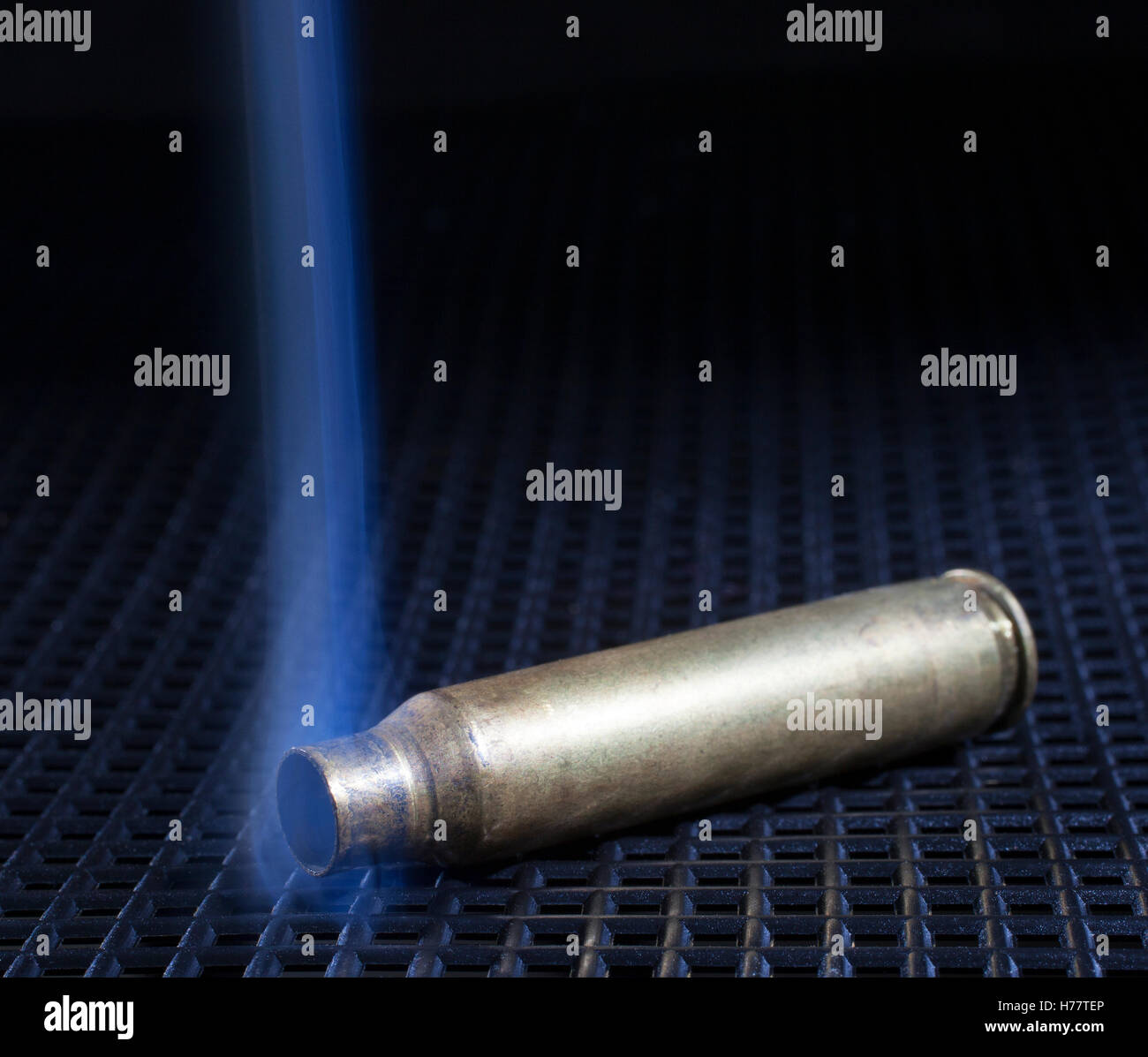 Brass casing from a rifle that has been shot and is pouring out smoke