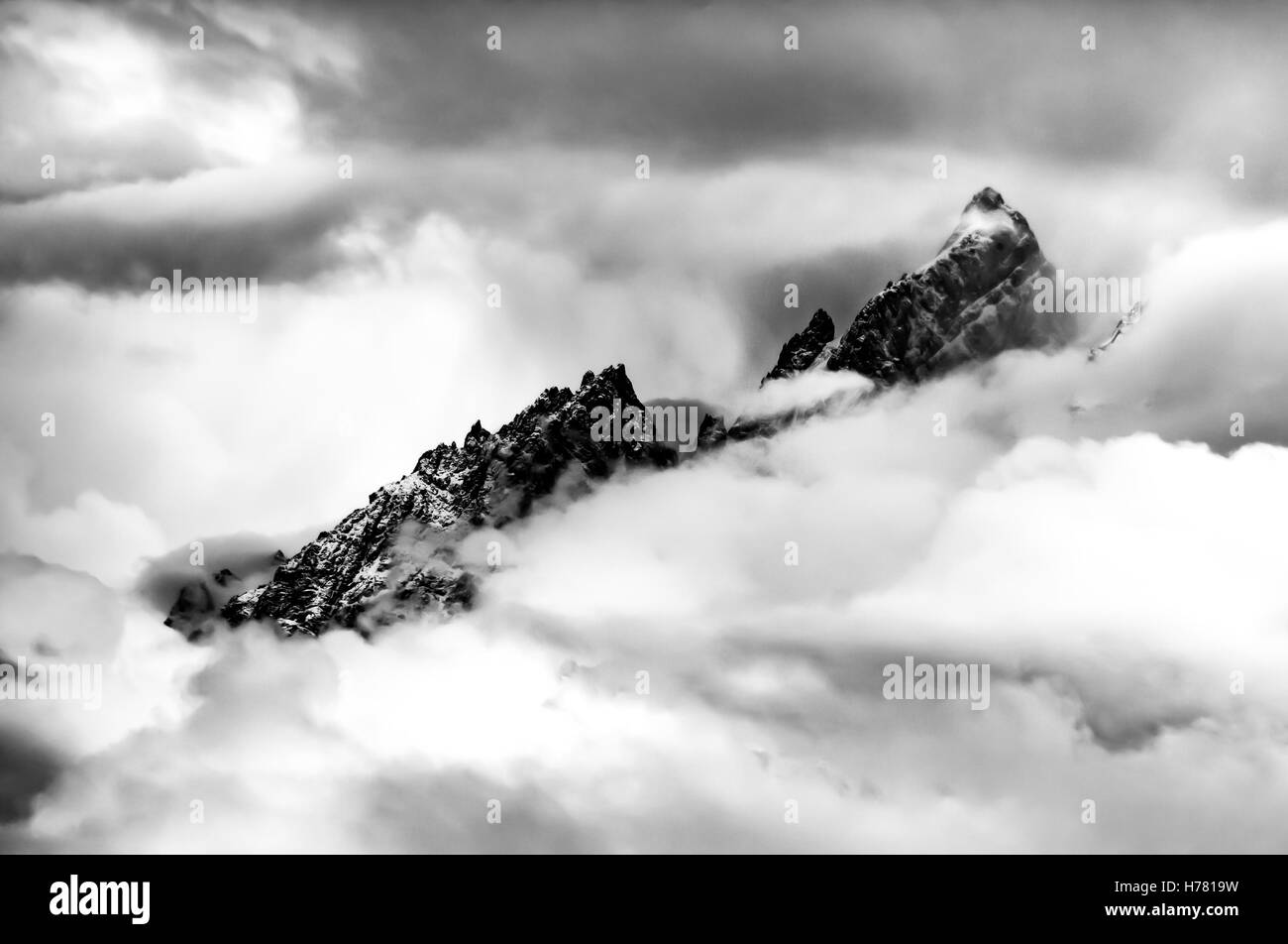 Snow Covered Teton Mountain Crest emerging above thick clouds Stock Photo