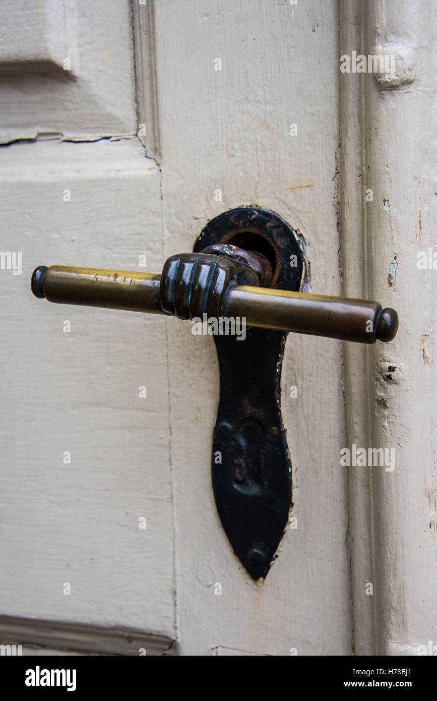 Unusual old brass door handle on an old white painted wooden door