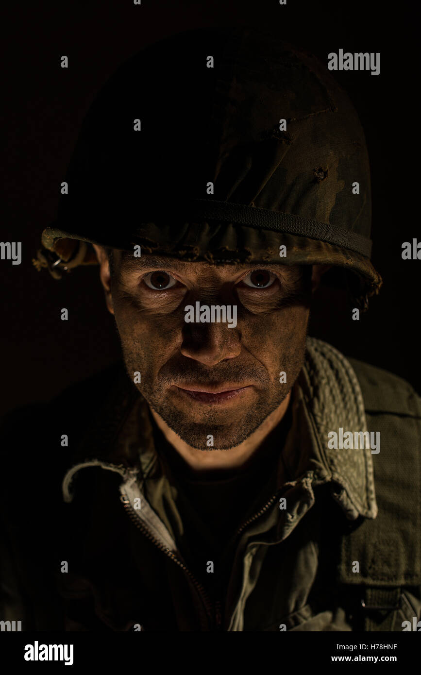 Portrait of a battle stressed American soldier from the Vietnam War, against a dark background. Stock Photo