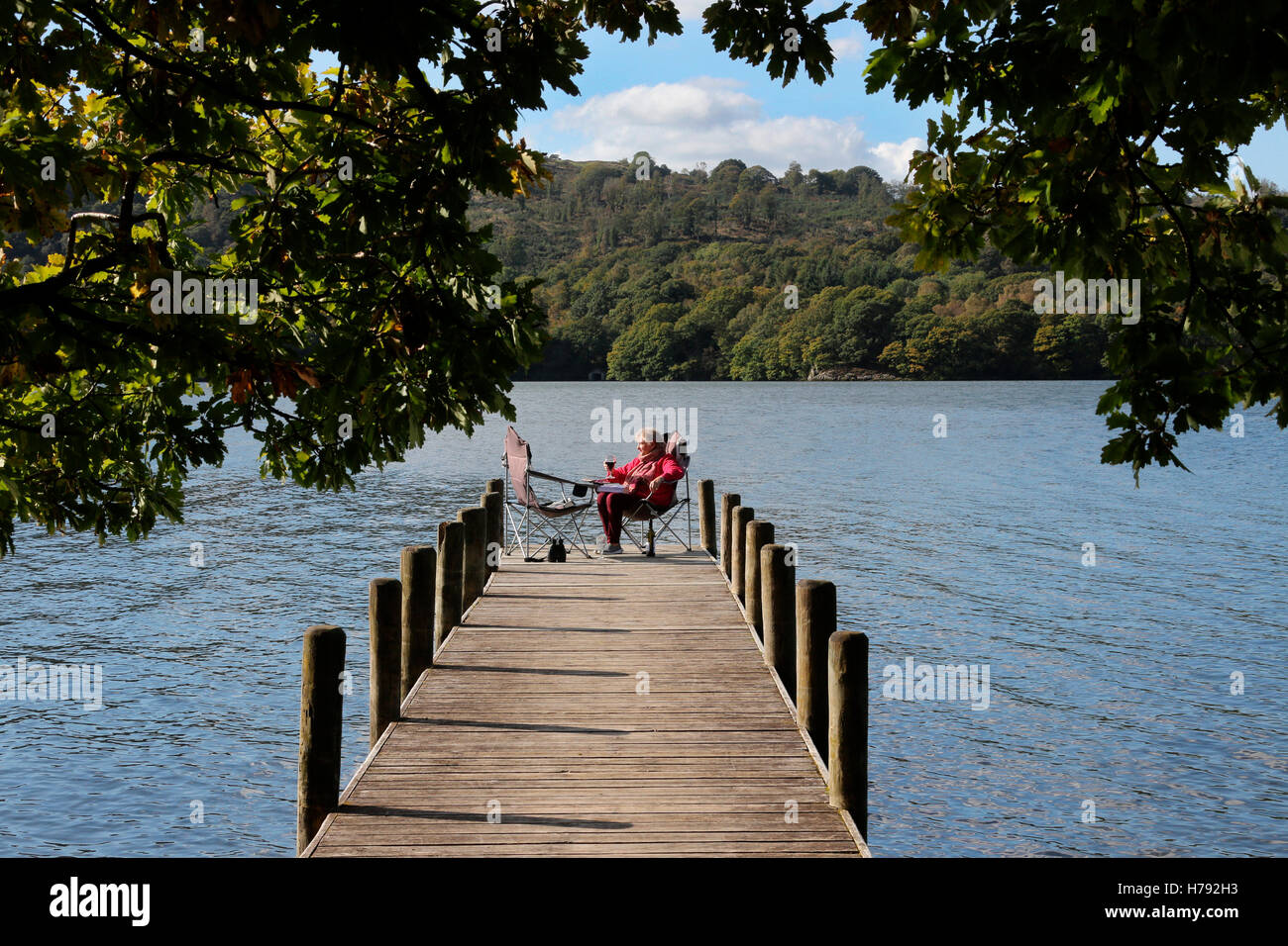 Relaxing on a jetty by Lake Windermere in the Lake District in Cumbria in the northwest of England in the United Kingdom. Winder Stock Photo