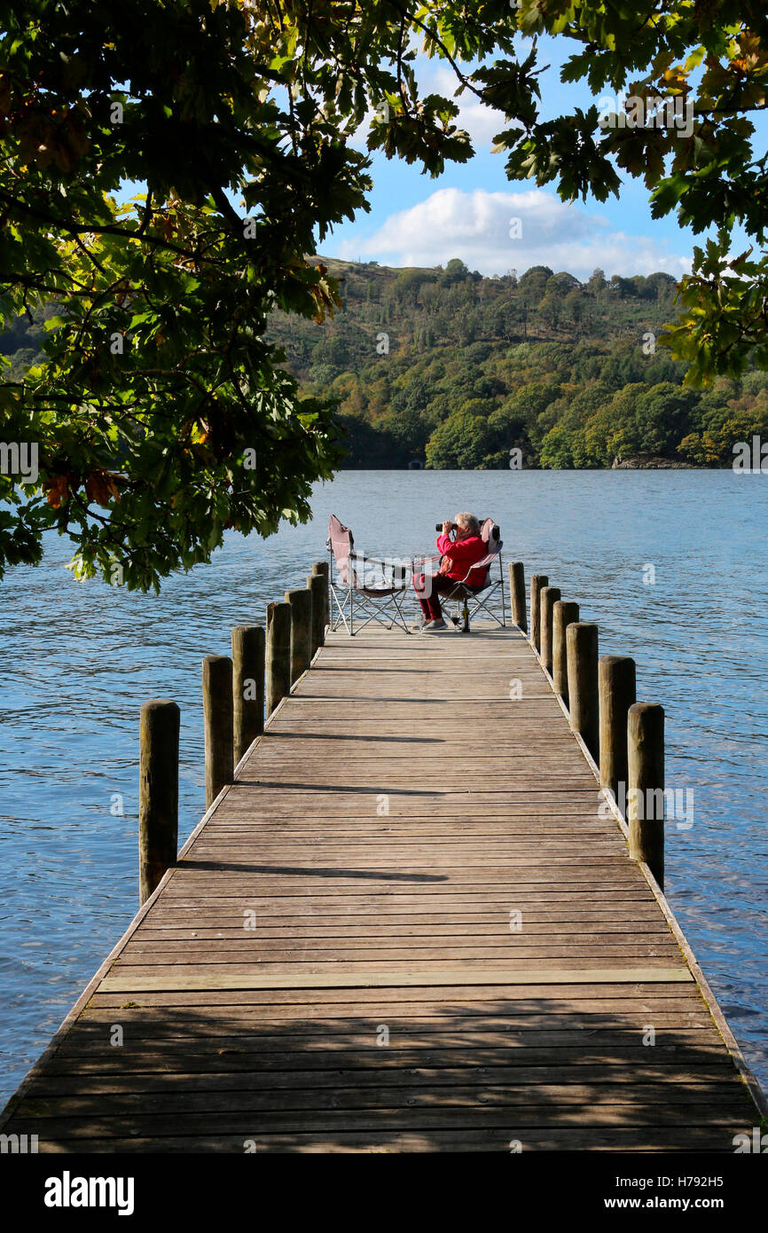 Relaxing on a jetty by Lake Windermere in the Lake District in Cumbria in the northwest of England in the United Kingdom. Stock Photo