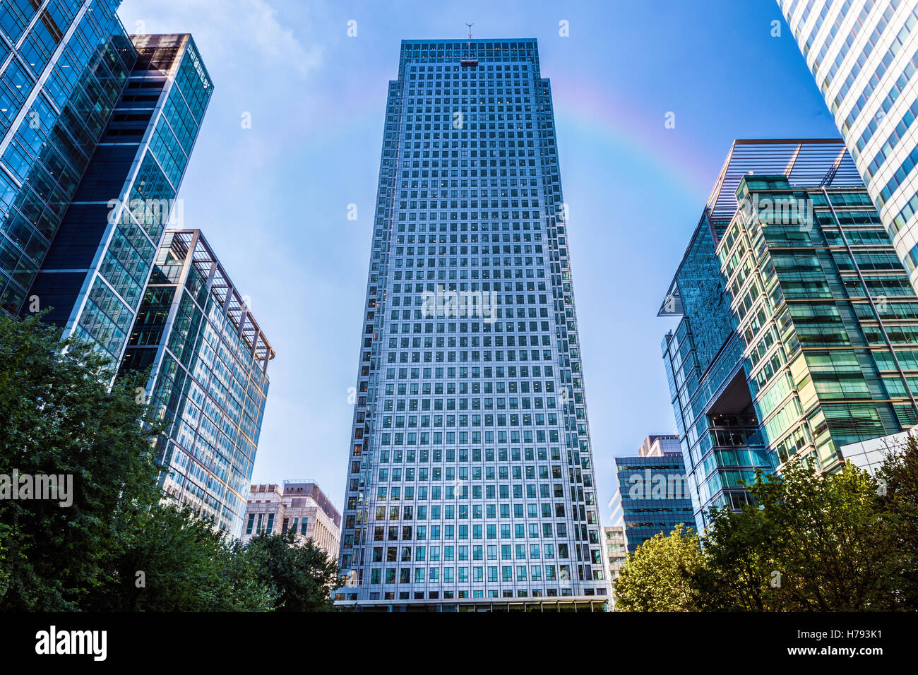 Office building in Canary Wharf, financial district of London with a faded rainbow in the background Stock Photo