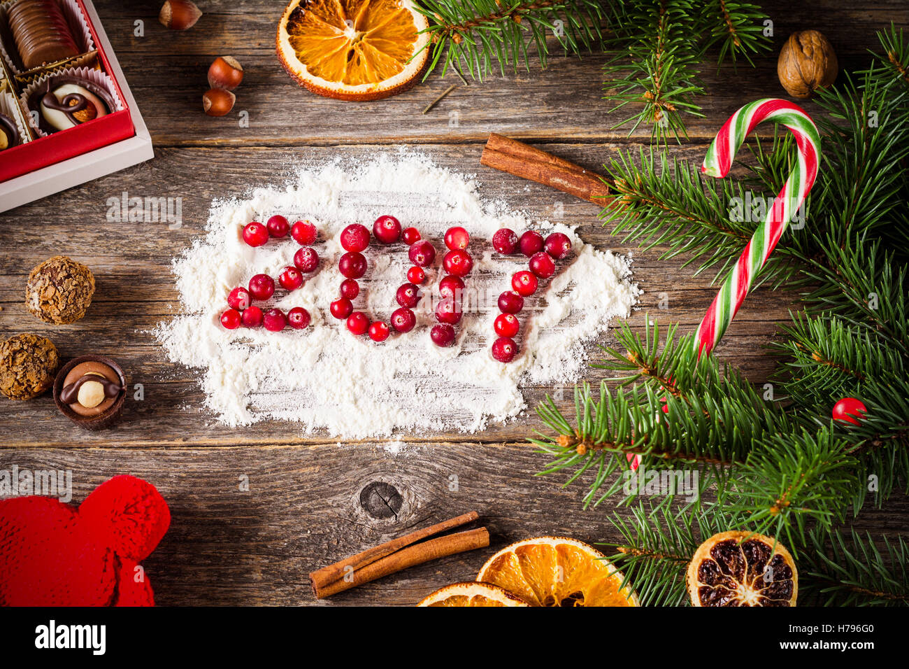 Happy New Year 2017 card ! Various candies, dried fruits, spices, fir tree and cranberries on wooden background with 2017 Stock Photo